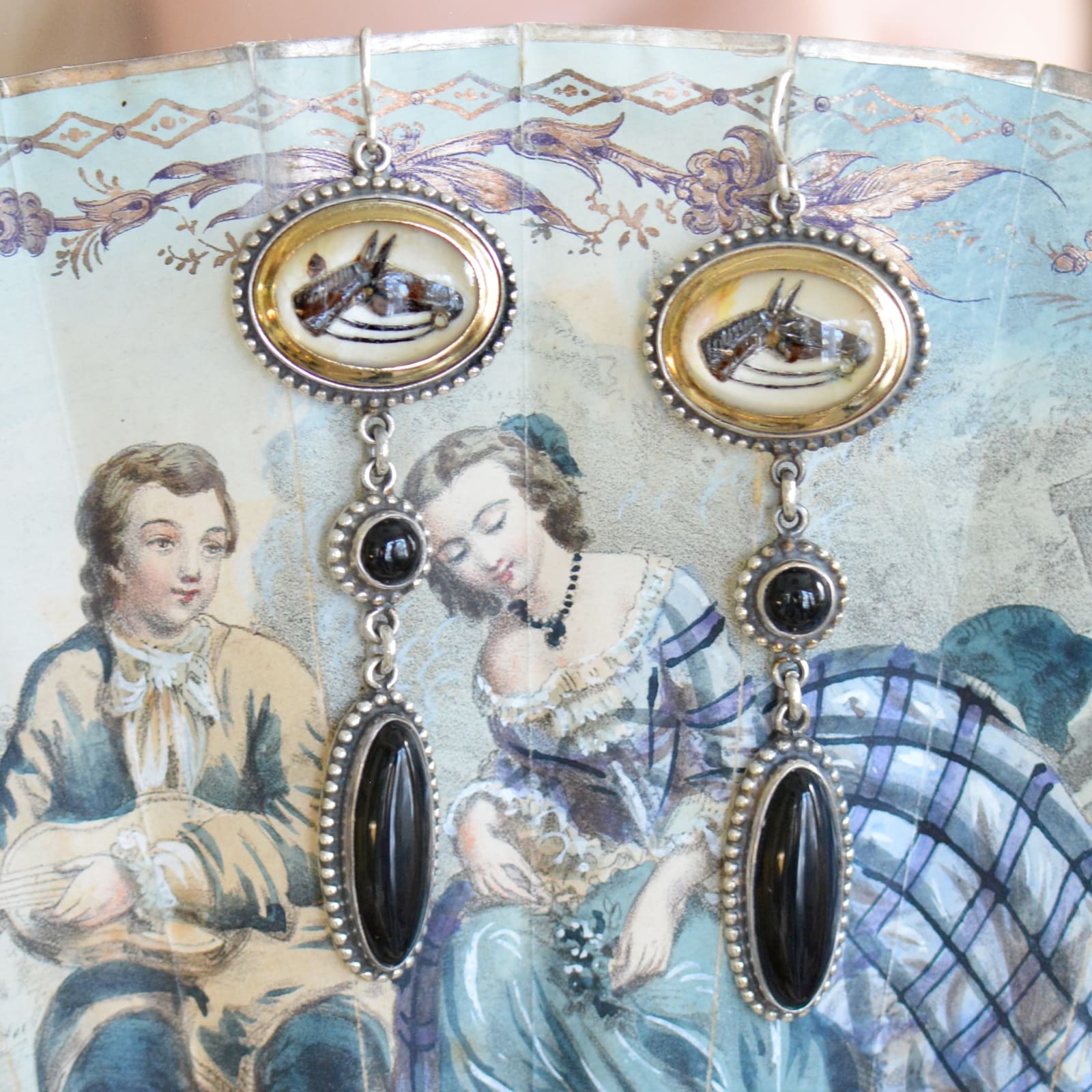 Jill Garber, A Handsome pair of attached wire chandelier earrings comprised of a set original early 20th Century English intaglio’s depicting horses heads that are rendered in various shades of brown, and black, reverse painted within crystal