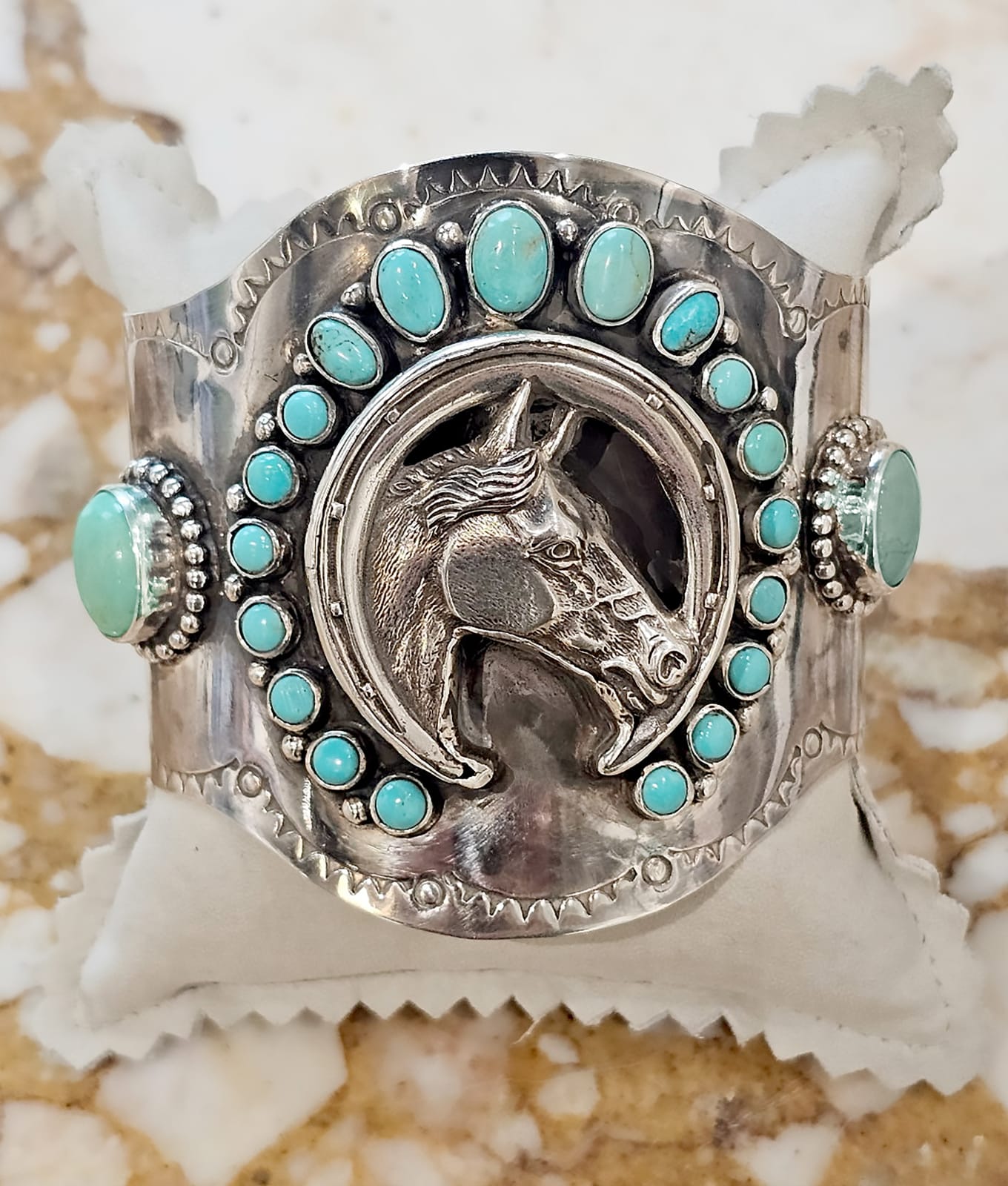 Jill Garber, A Western inspired Luck Boy cuff bracelet honoring Jill’s Doc Bar quarter Horse “Cash” is surrounded with a shoe shaped wreath of greenish aqua kingman turquoise cabochons