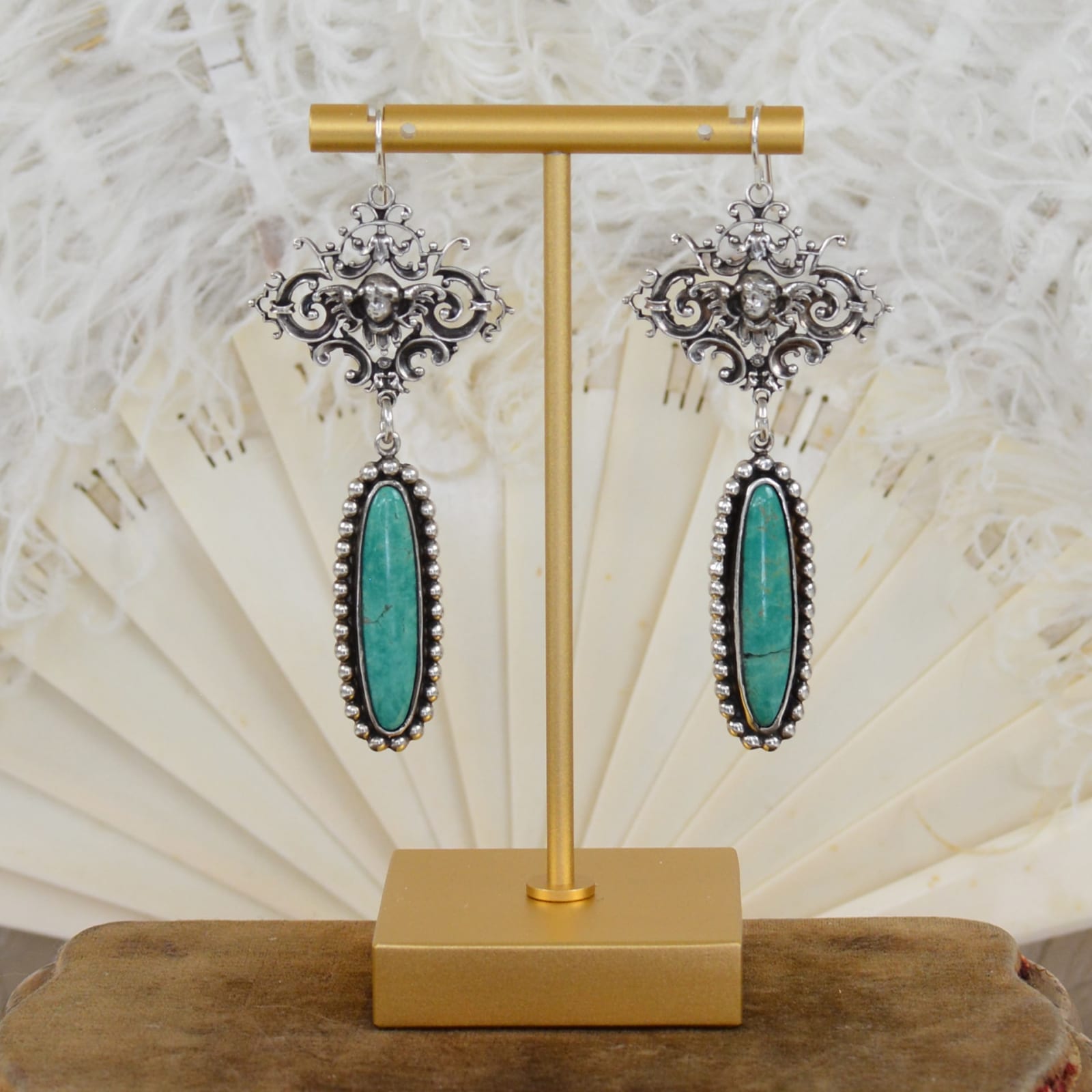 Jill Garber, Romantic hand cast figural ornamentation in sterling silver form these lovely chandelier earrings with long deep aqua blue – green kingman turquoise cabochons drops