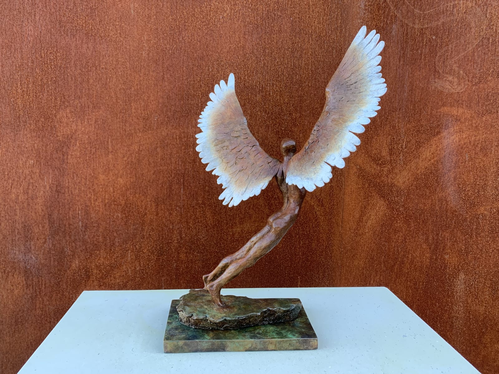 Figurative bronze sculpture of mythical Greek winged figure Icarus by Nicola Godden, displayed on plinth.