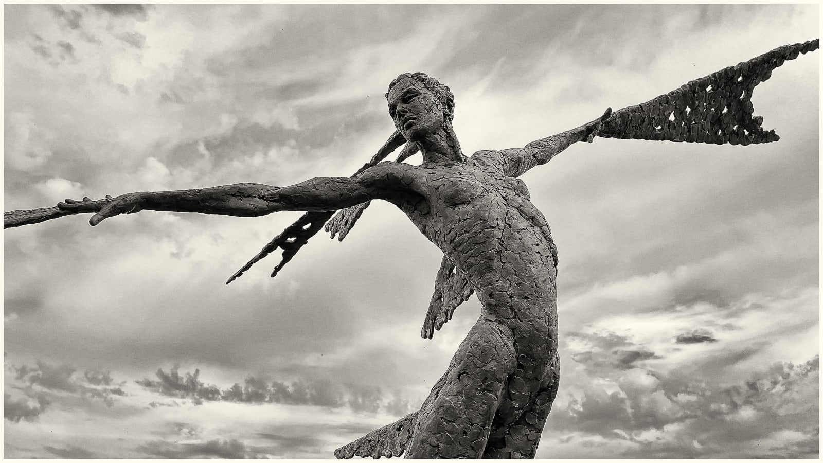 A monumental bronze sculpture of a winged female set against sky at a Dorset sculpture park, Sculpture by the Lakes,