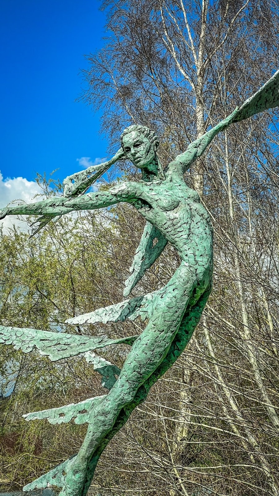 A monumental bronze sculpture of a winged female stands in front of trees at a Dorset sculpture park, Sculpture by the Lakes