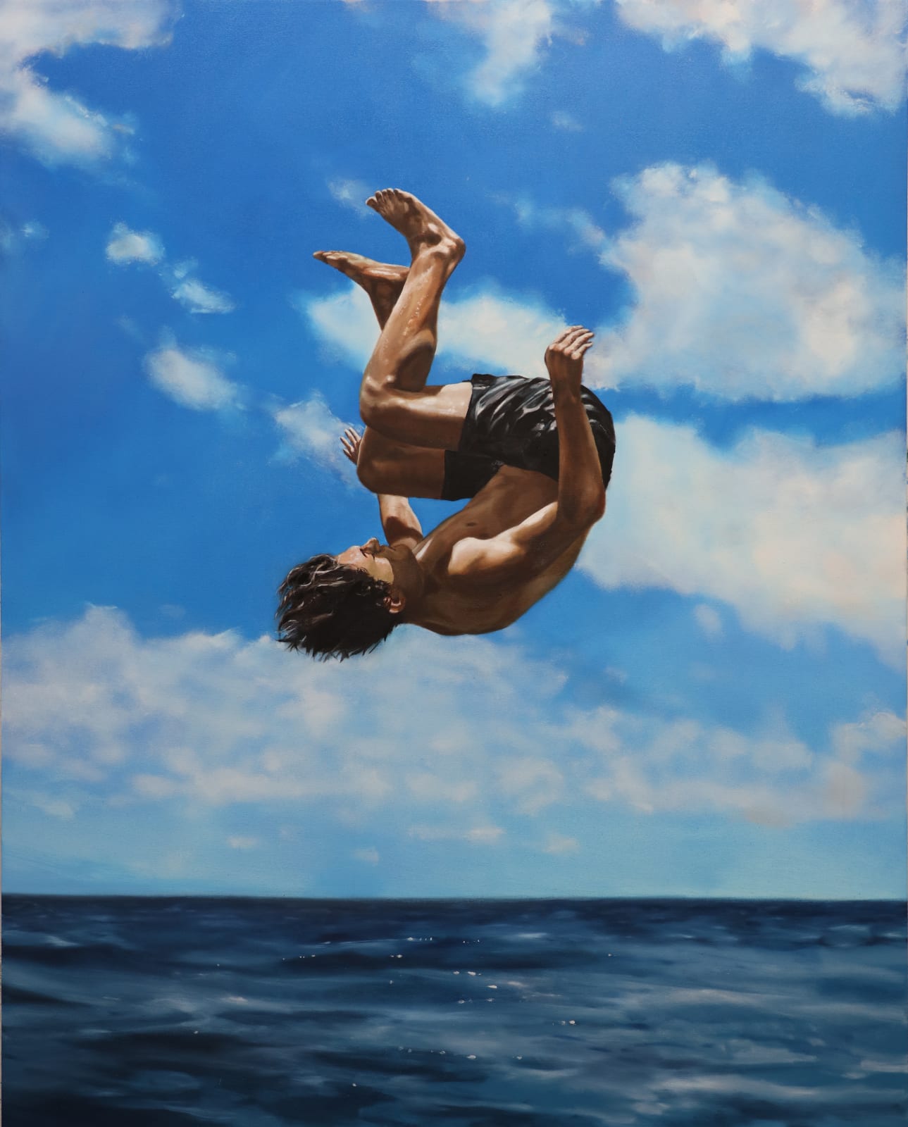 Man in bathing suit doing a cannon ball dive through the air above water