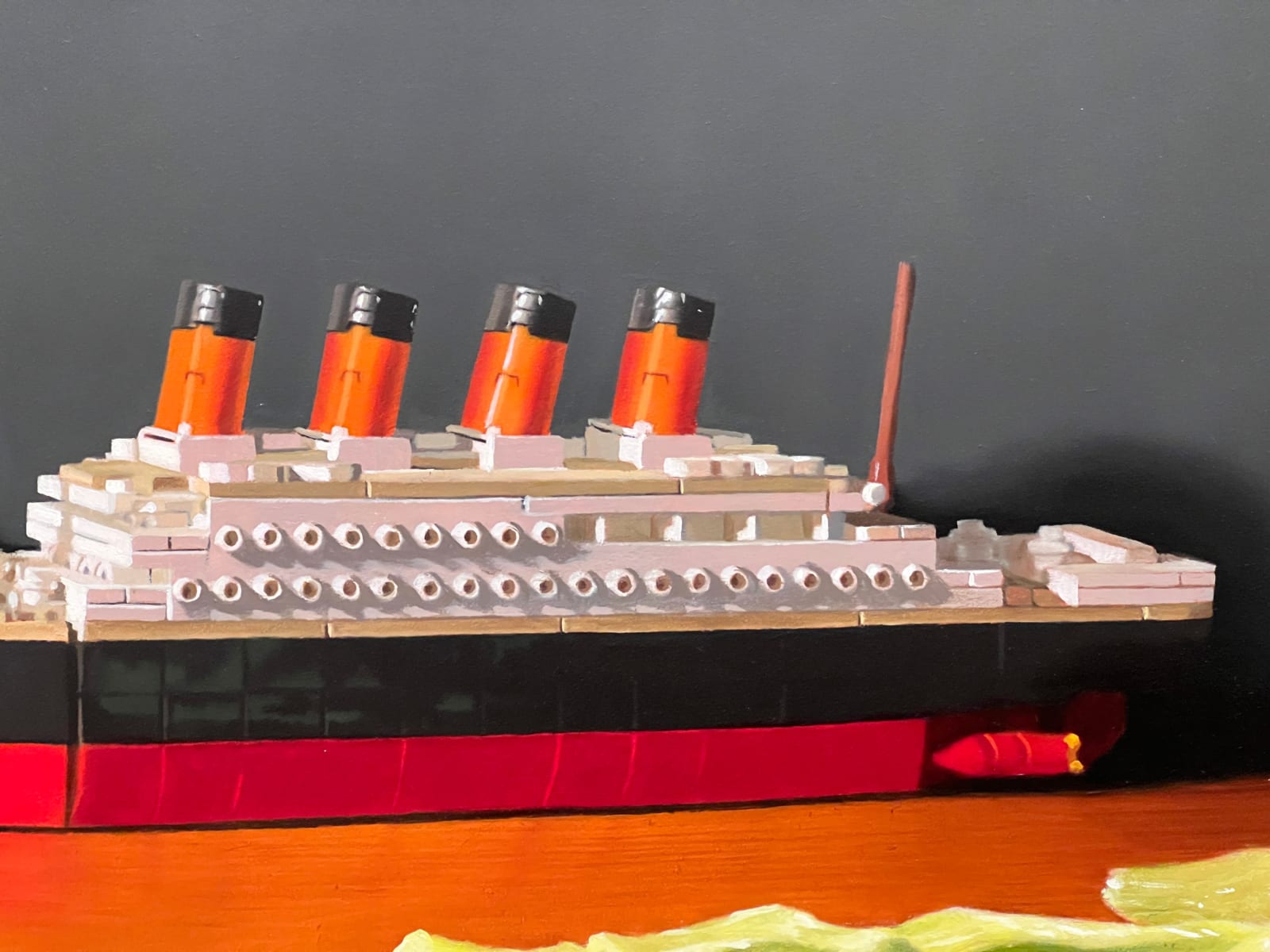 Detail of toy boat in A toy replica of the HMS Titanic is placed amongst the cut up pieces of a head of iceberg lettuce.