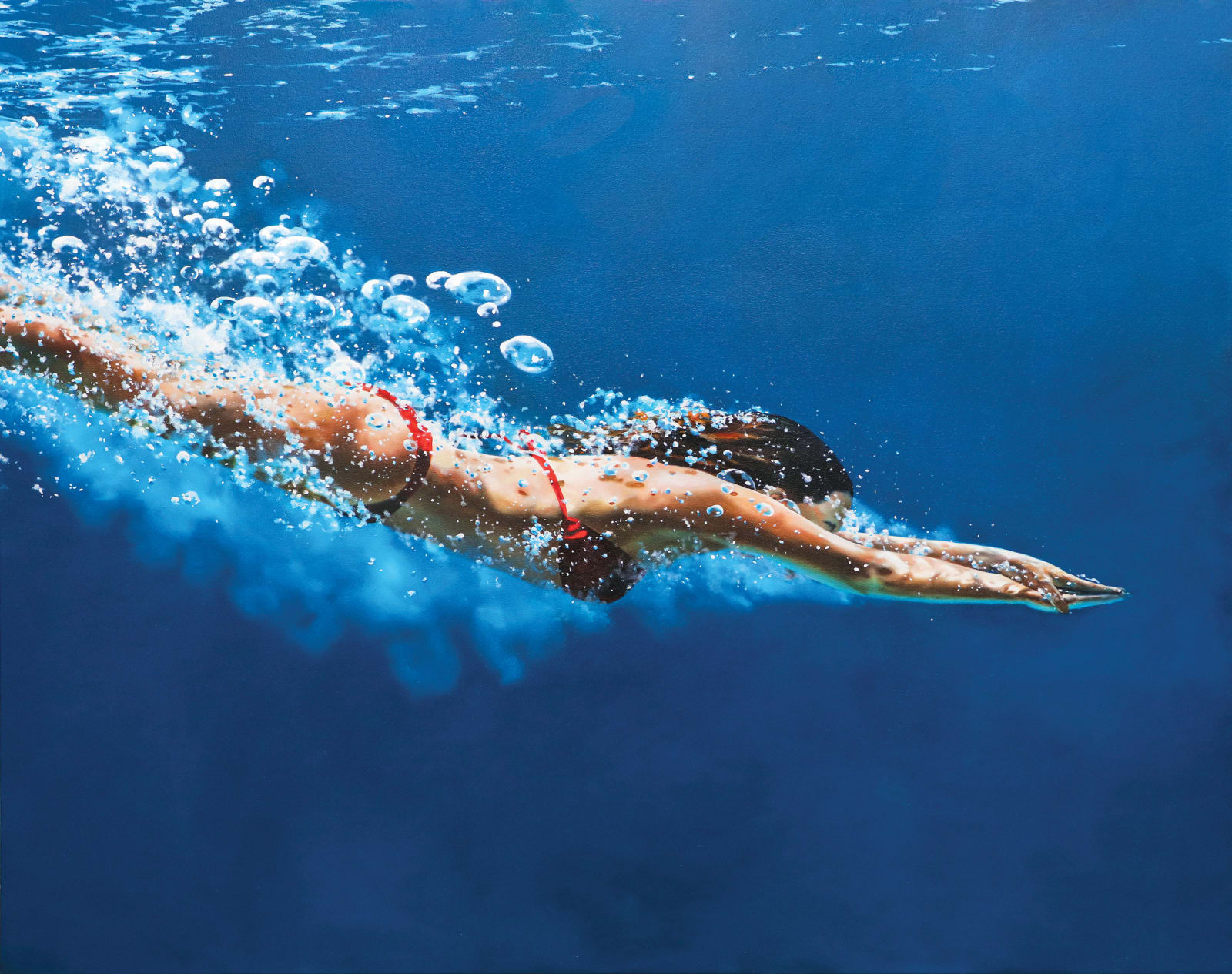 Woman in a red bikini diving through blue water
