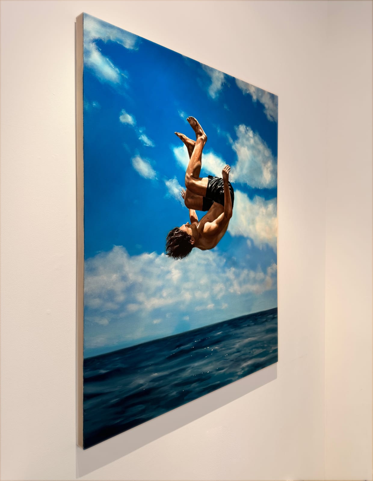 Man in bathing suit doing a cannon ball dive through the air above water