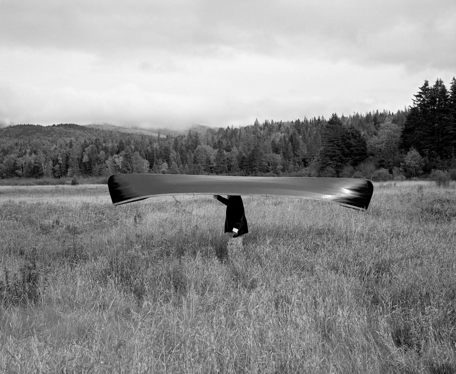 Rodney Smith photograph man walking in a field balancing an upsidedown canoe on his head buy here Gilman Contemporary