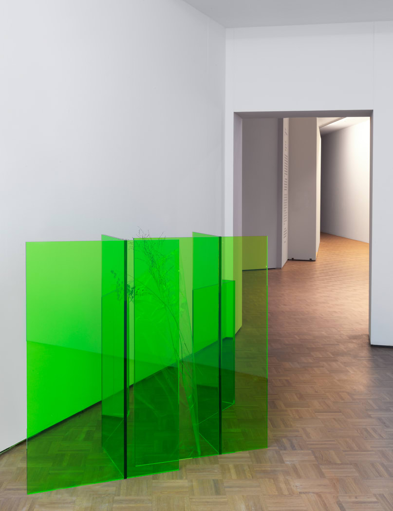 a lime green folded plexiglass formation standing upright within a room.