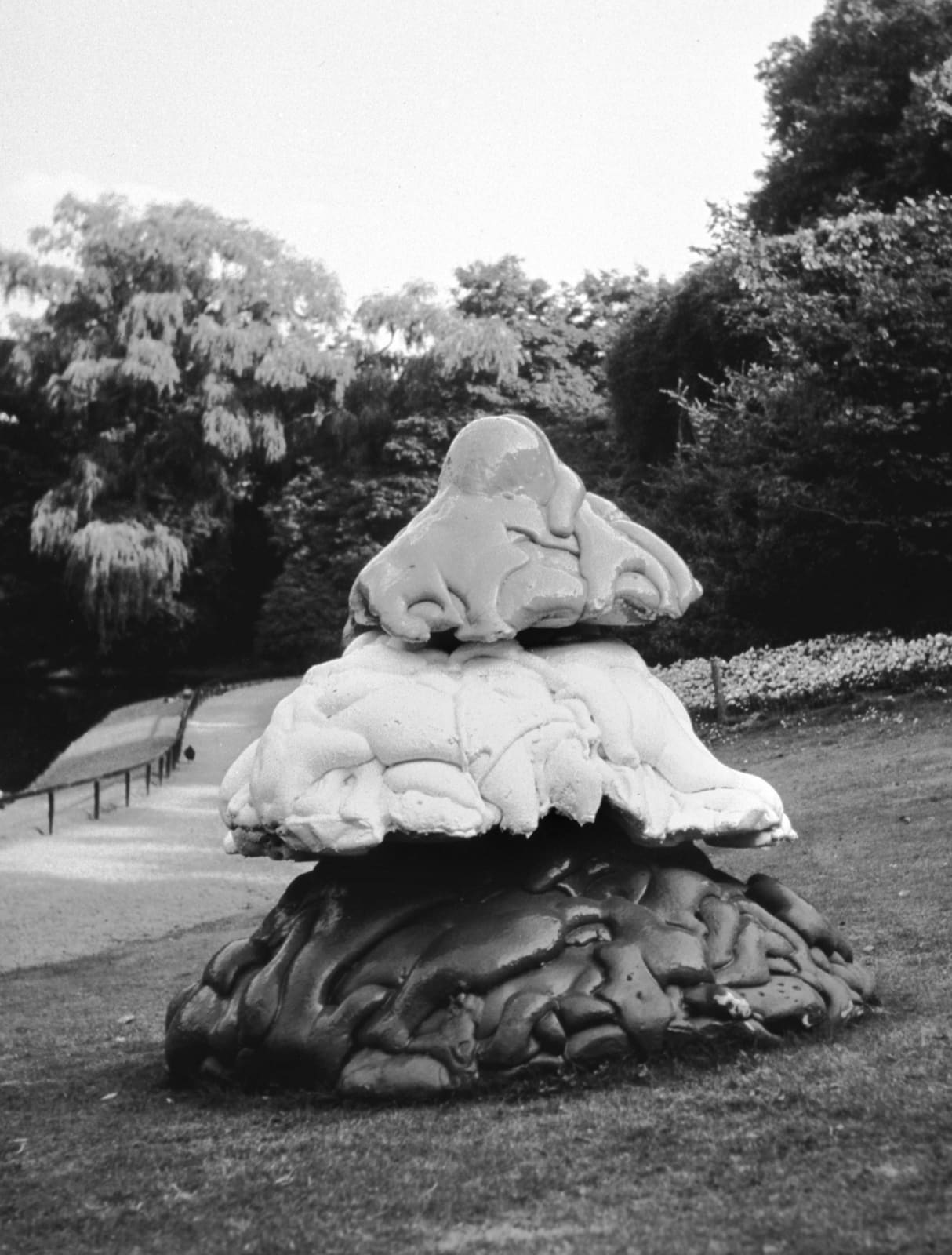 An outdoors sculpture of three rock-like shapes stacked on top of each other.