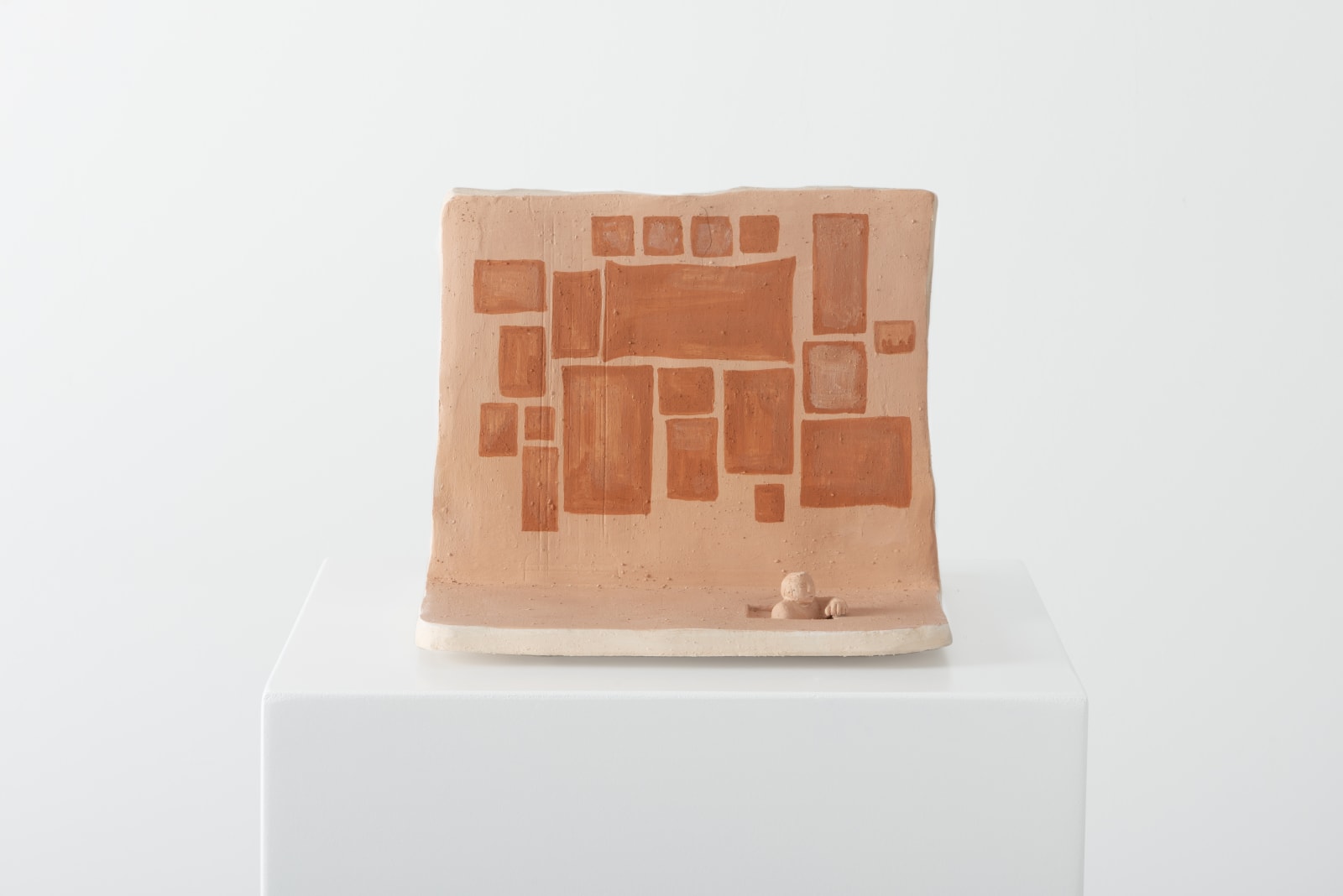 opposite side of the ceramic piece depicting a figure emerging from a hole in the ground in some sort of gallery space