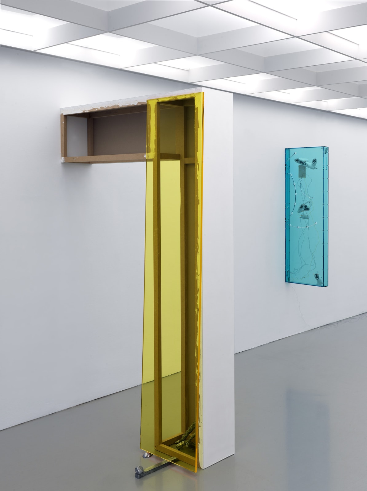 a post-and-beam-like structure coming out of a white wall to form an arch, colored with yellow plexiglass on one side.