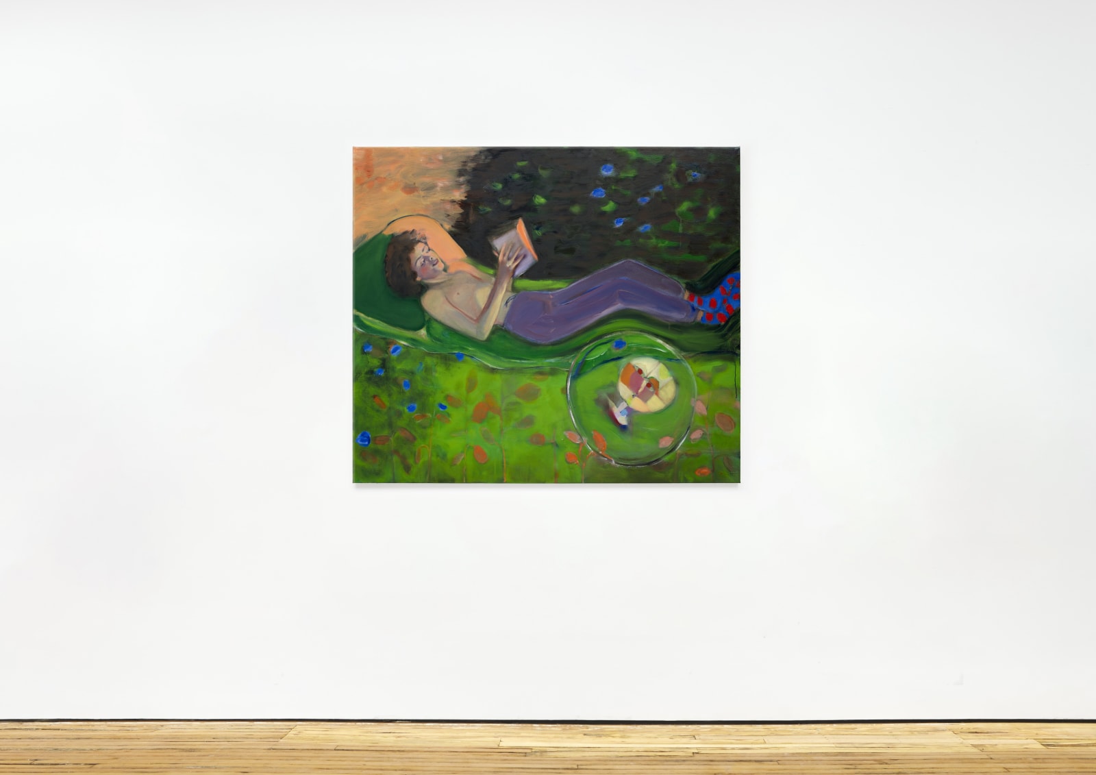 installation image of an oil painting depicting a boy reclining in a garden and reading a book