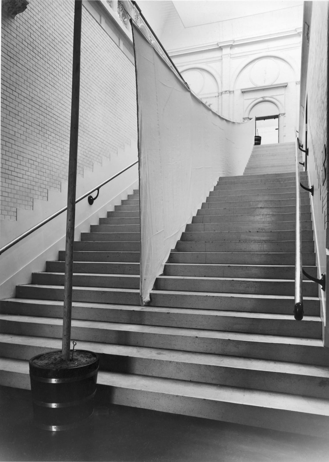 A black and white image of a stairwell with some kind of sculpture running down the center.
