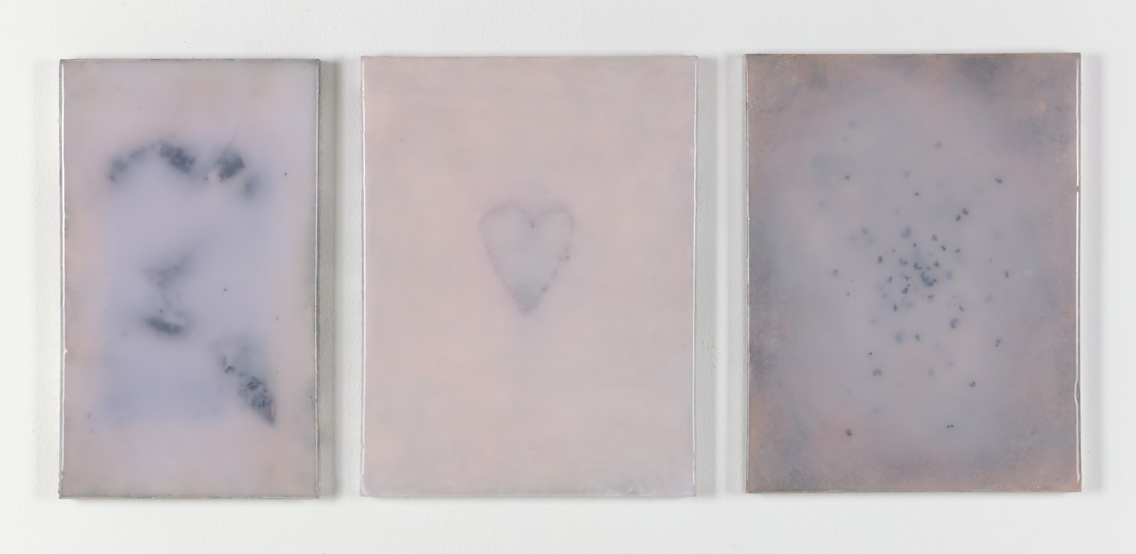 An image of three pink pigmented panels, each made out of rigid foam, rubber, and poppy seeds, the center piece has seeds in the shape of a heart.