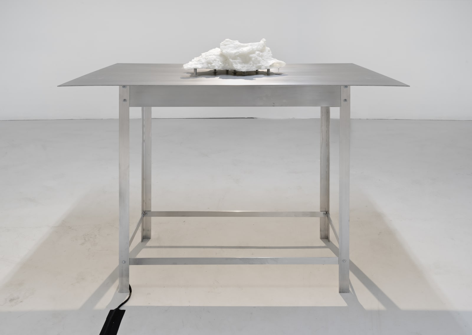 A white sculpture sitting on an aluminum table.