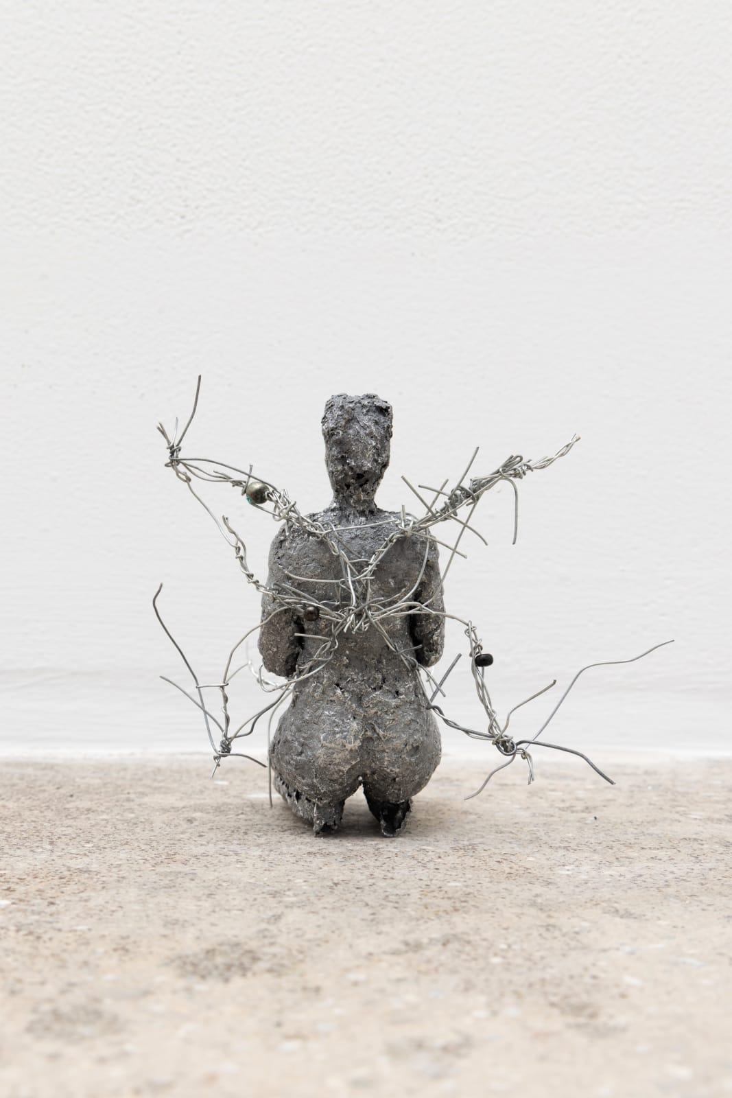 Free-standing sculpture made from lost-wax cast aluminum featuring a kneeling human figure with wires emanating from the back like a pair of wings. 