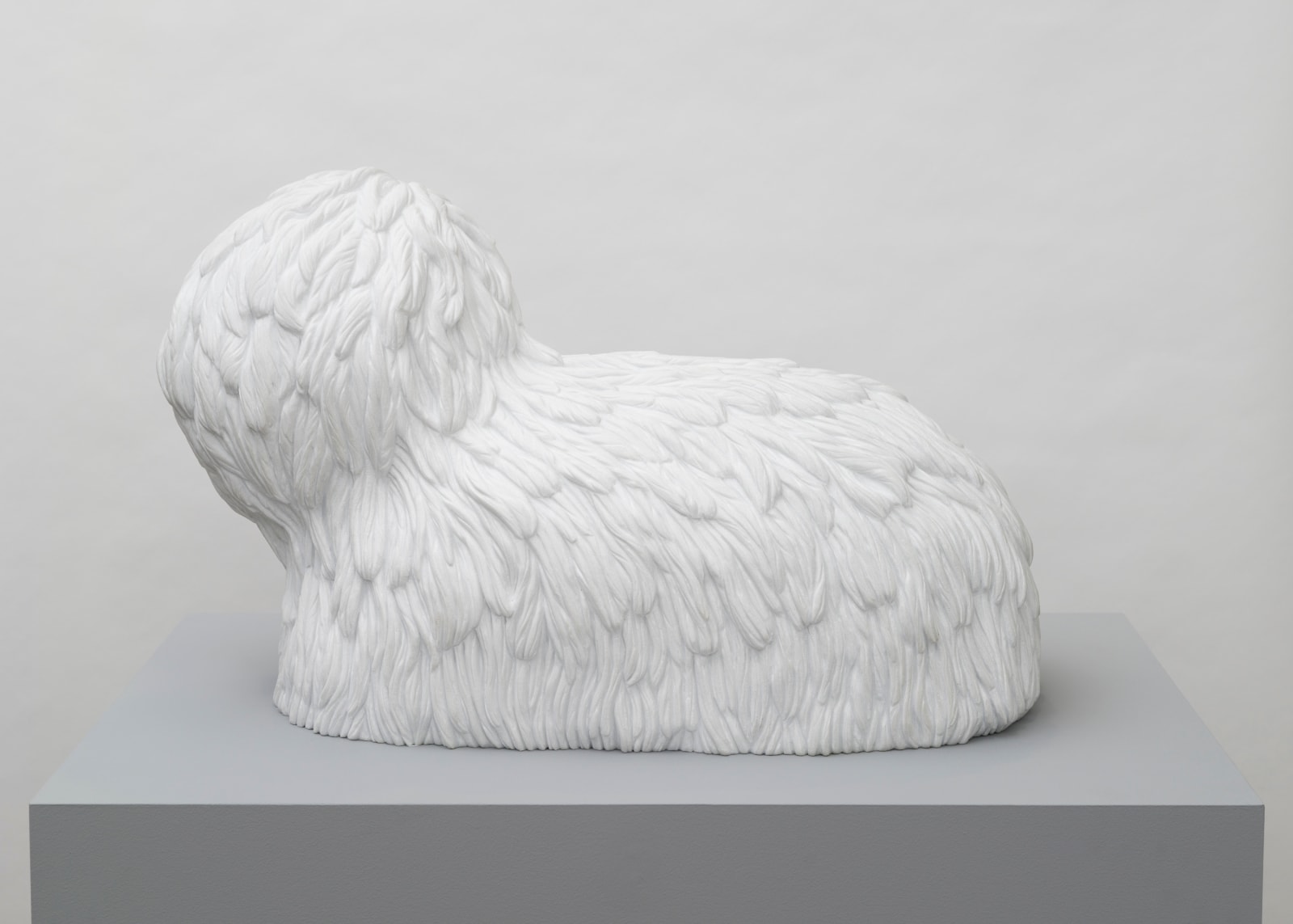 Free-standing, white marble sculpture in the form of a poodle-like creature whose entire surface is carved to give it fur-like texture.