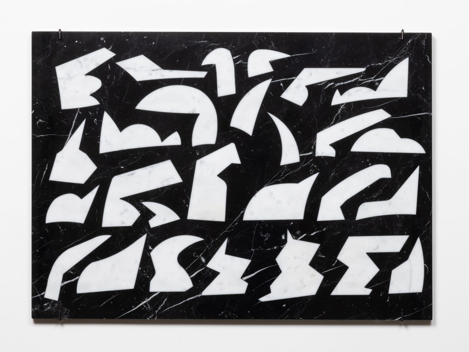 Wall-mounted, black rectangular marble slab inlaid with several white marble shapes resembling abstract bird-like forms with beaks.