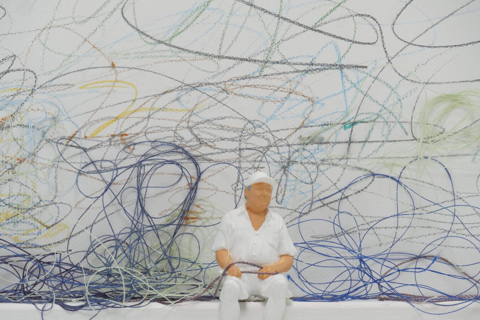 Detail of man sitting on ledge with thread.