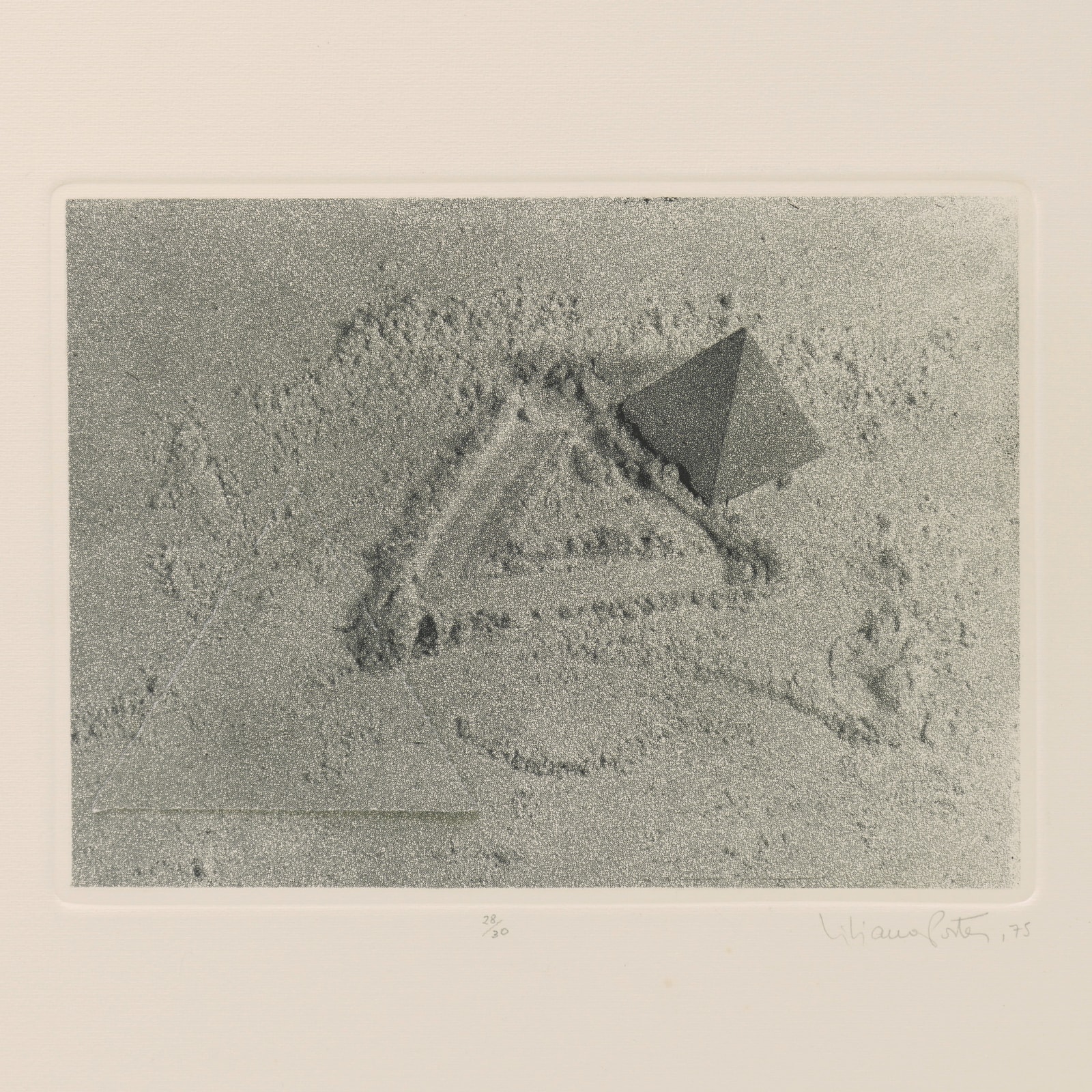 Closer detail of print with white border of sand with pyramid, triangle cut into sand, and cut triangle matching print.