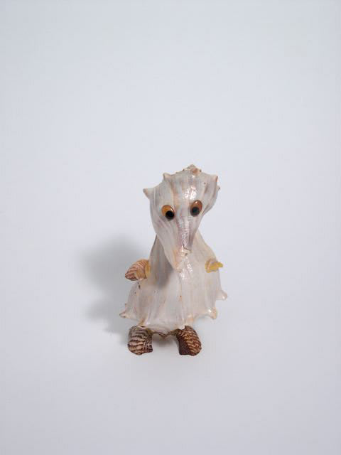Archival digital photograph of a small humanoid figurine made out of multiple different shells. One of the several translations for the spanish word caracol is shell or conch.