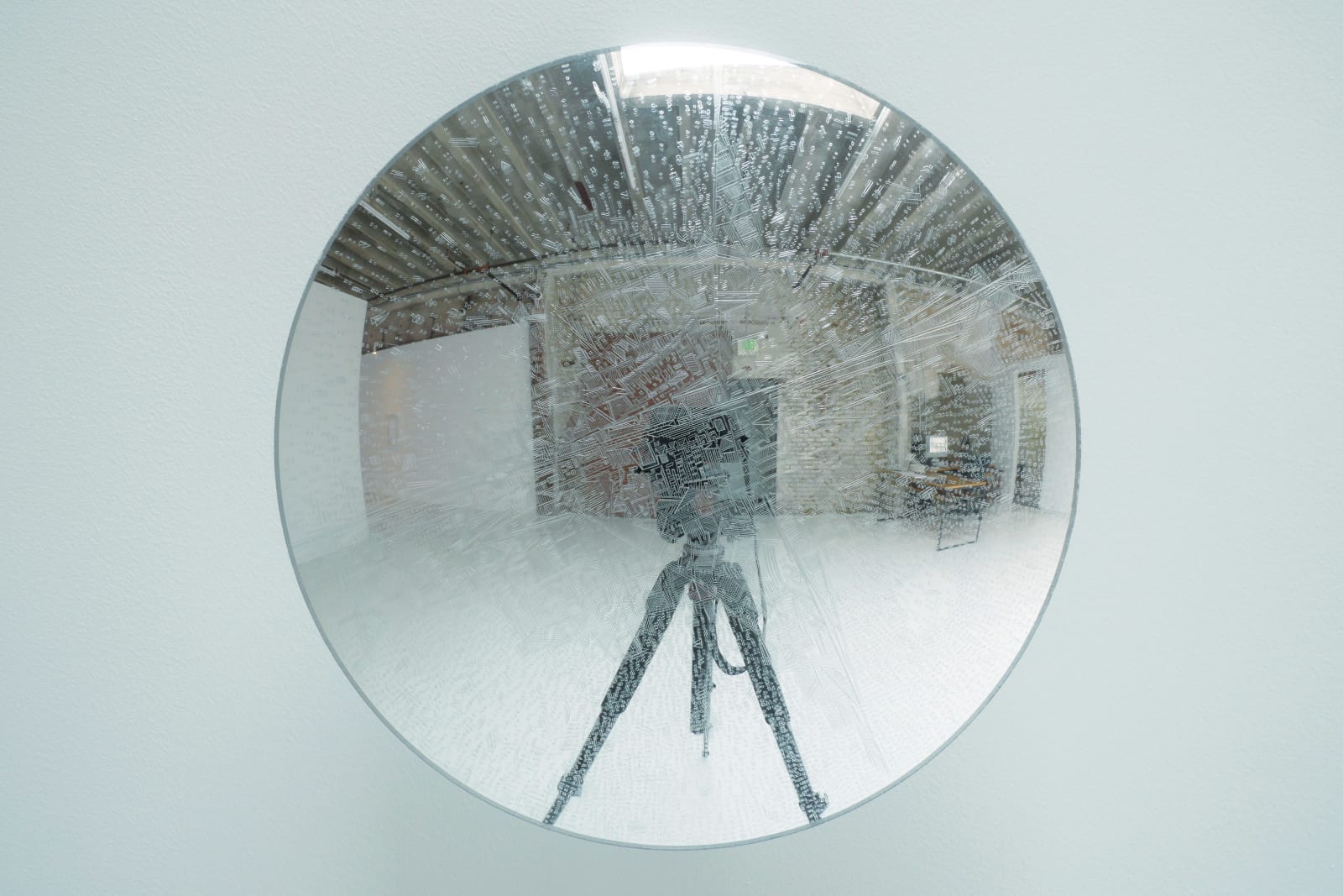 Front view of engravings on a clear disk, with reflection of tripod.