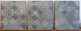 Three separate dark gray panels with several silkscreen layers of white black and gray acrylic paint overlap and display multiple patterns The patterns depict various asian motifs and in the rightmost panel a gray silhouette of a ballet dancer is also visible
