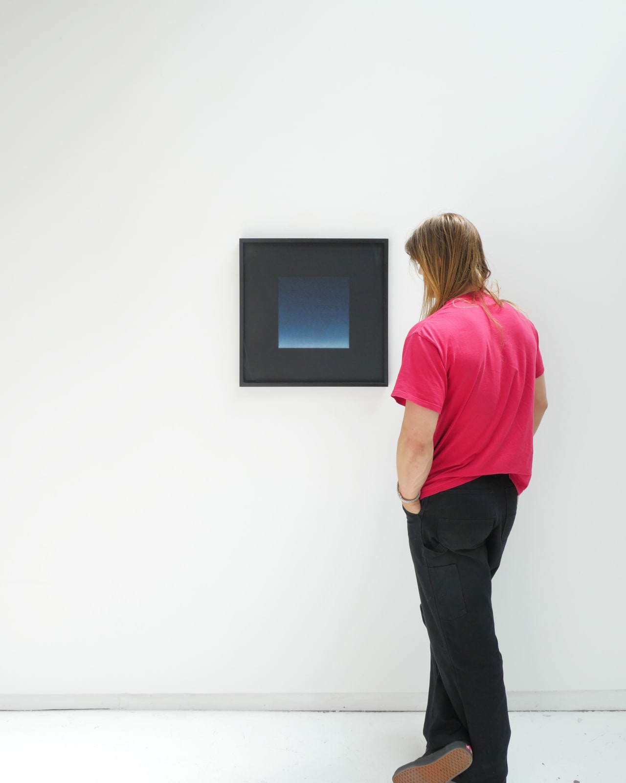 A white man admires framed Floating Phthalo Blue Square hanging on a white wall