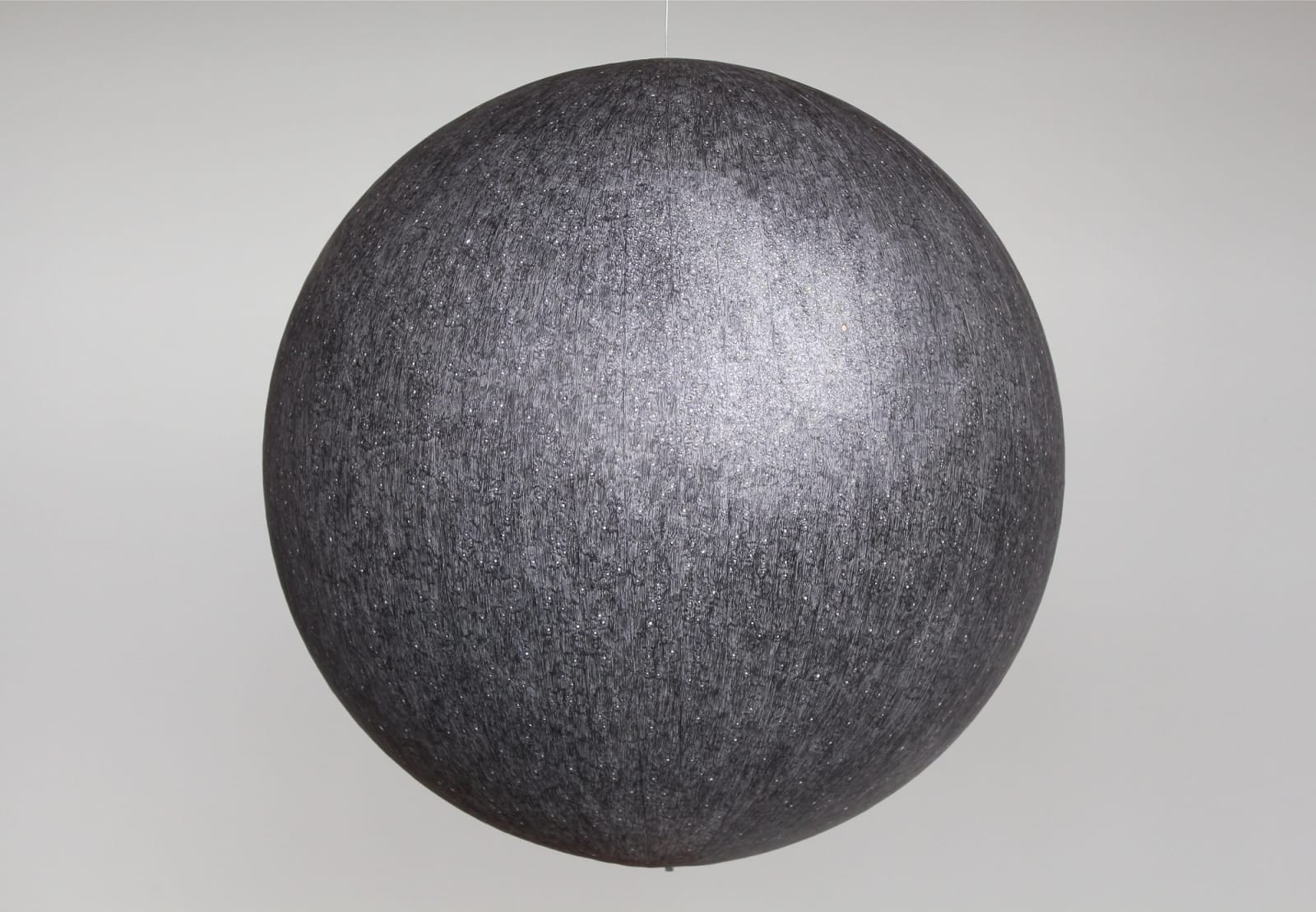 Black and white ballpoint pen drawing with washes of watercolor create a galactic scene with multiple stars on paper which is pasted onto a large acrylic hanging globe