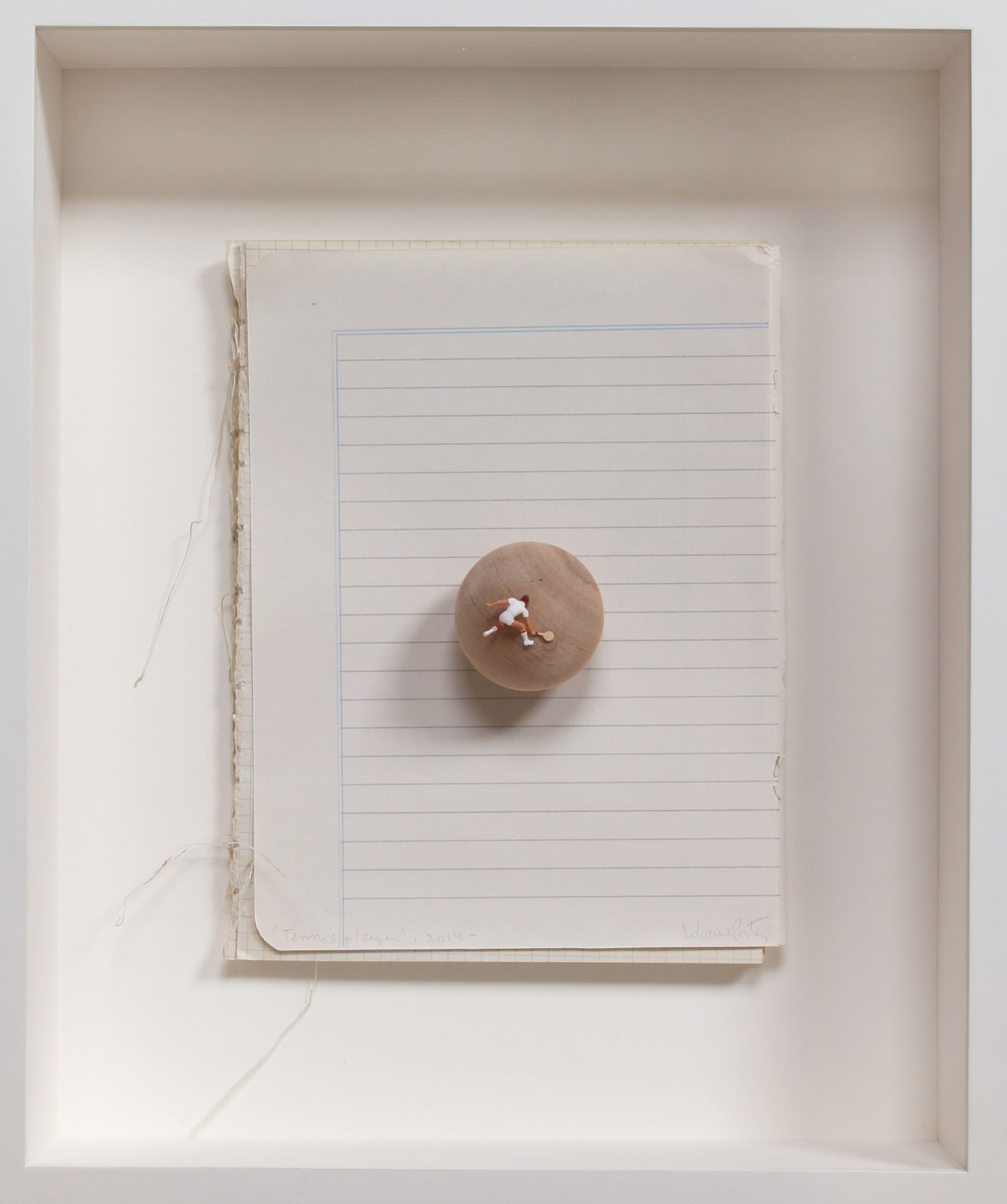 Collage made out of a small wooden sphere mounted onto the old lined paper of a notebook. On the surface of the sphere a tiny human figurine holds a tennis racket and holds a tennis pose