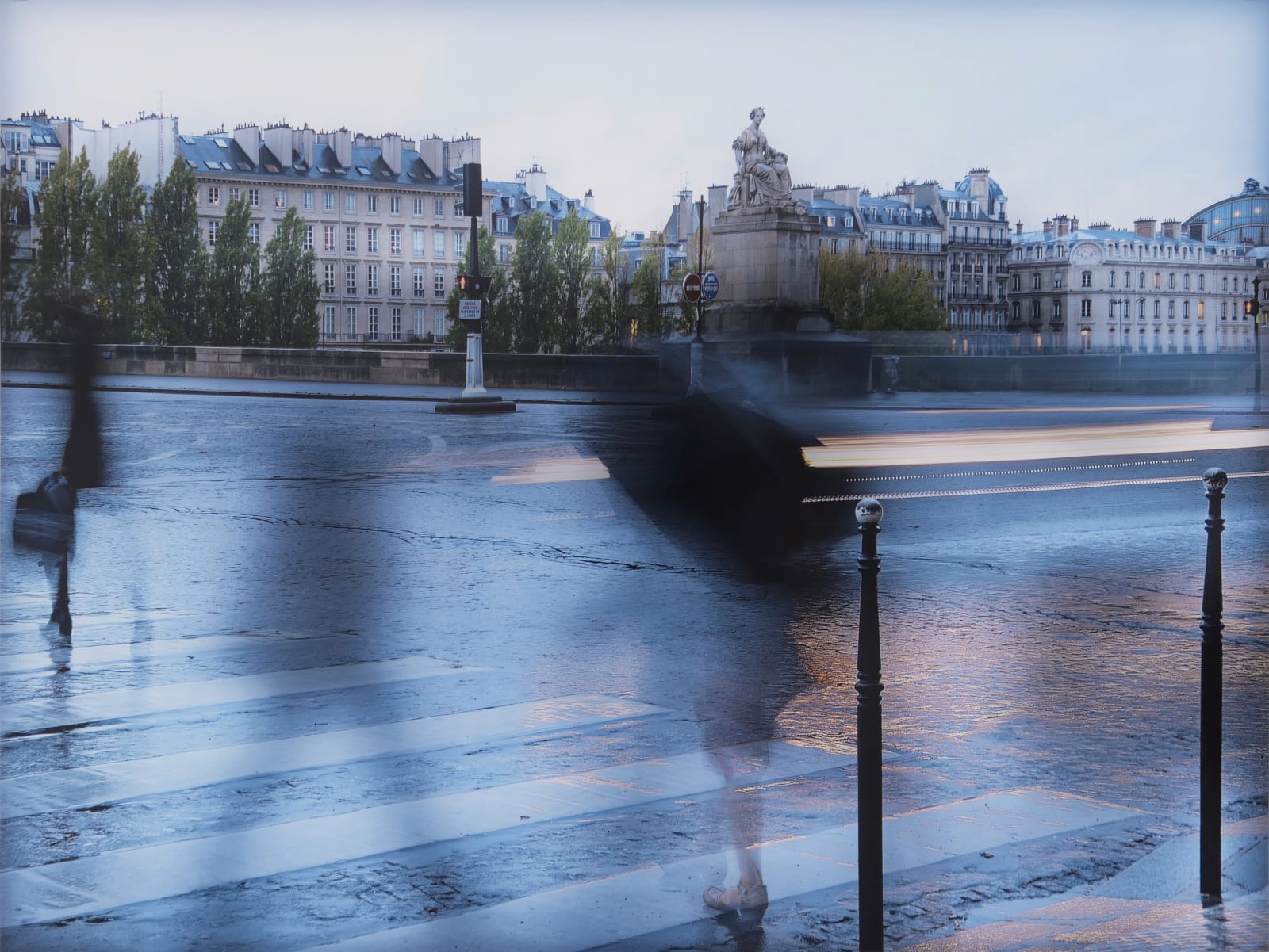 Faint figures crossing in crosswalk in rainy Paris.