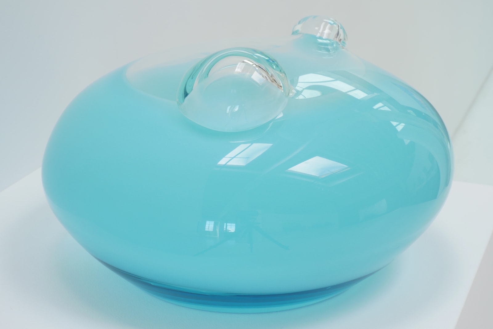 A light blue UFO-shaped sculpture with two clear bubbles on top, side view on pedestal.