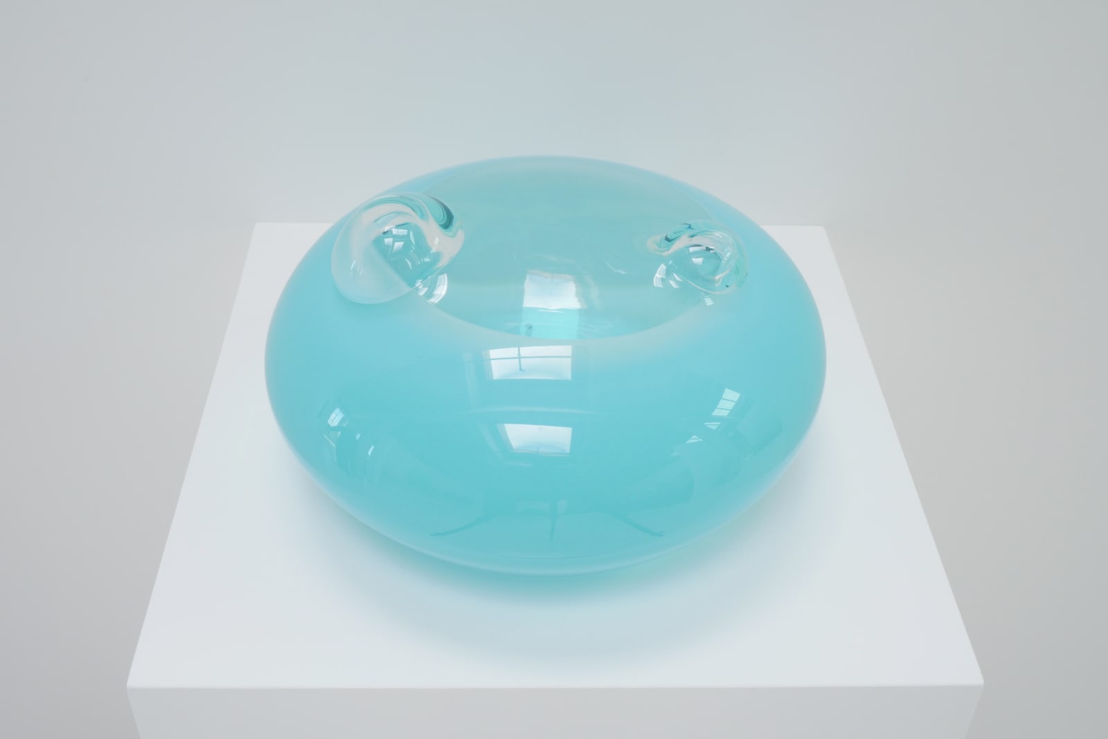 A light blue UFO-shaped sculpture with two clear bubbles on top, top view on pedestal.