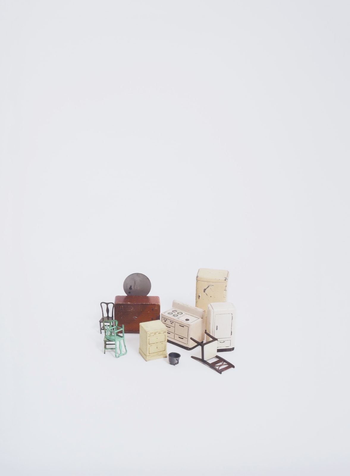 A photograph with dollhouse furniture clustered at the center on a white background