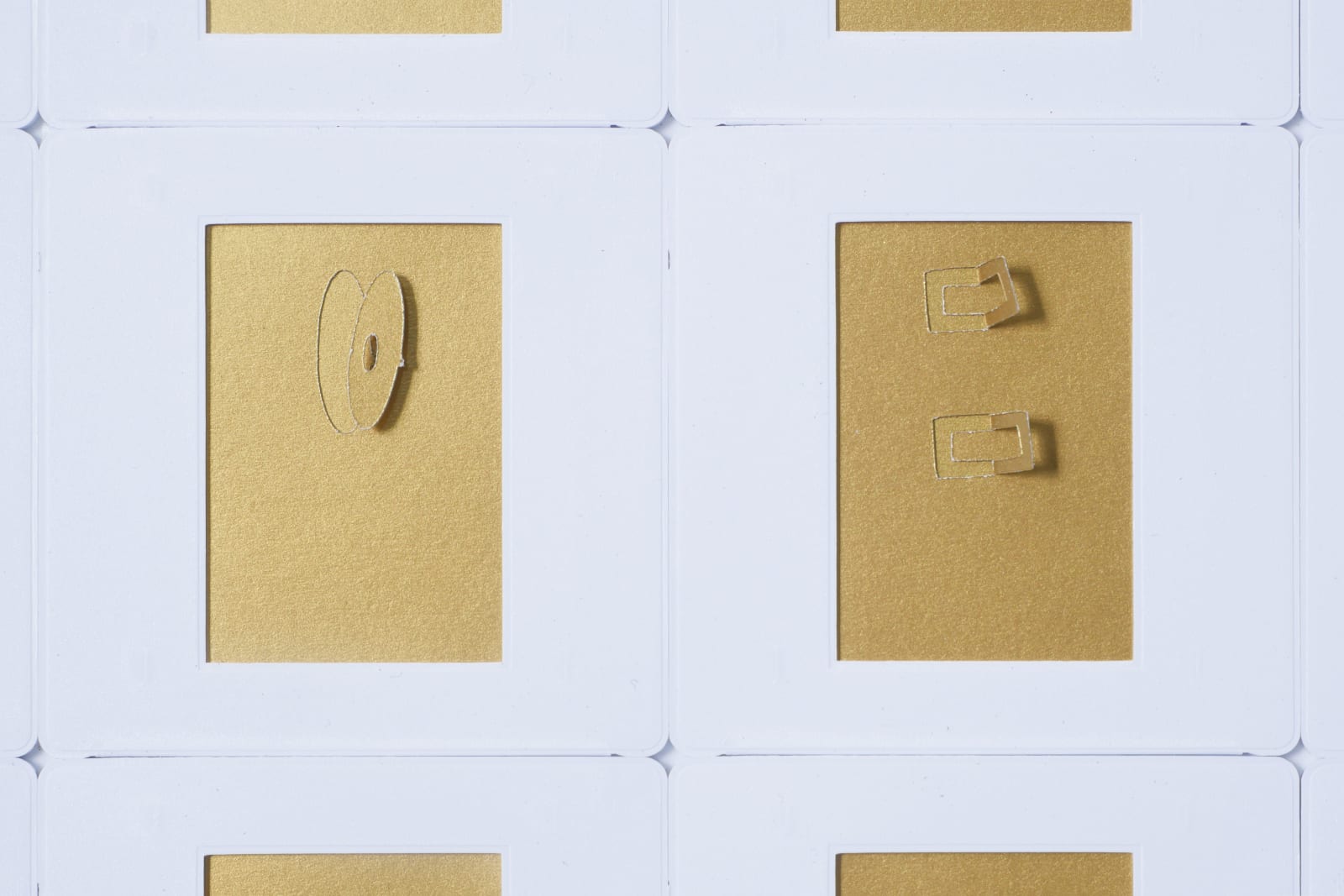 Detail; two of the gold rectangles on white background. Various cutouts and flaps on each rectangle.
