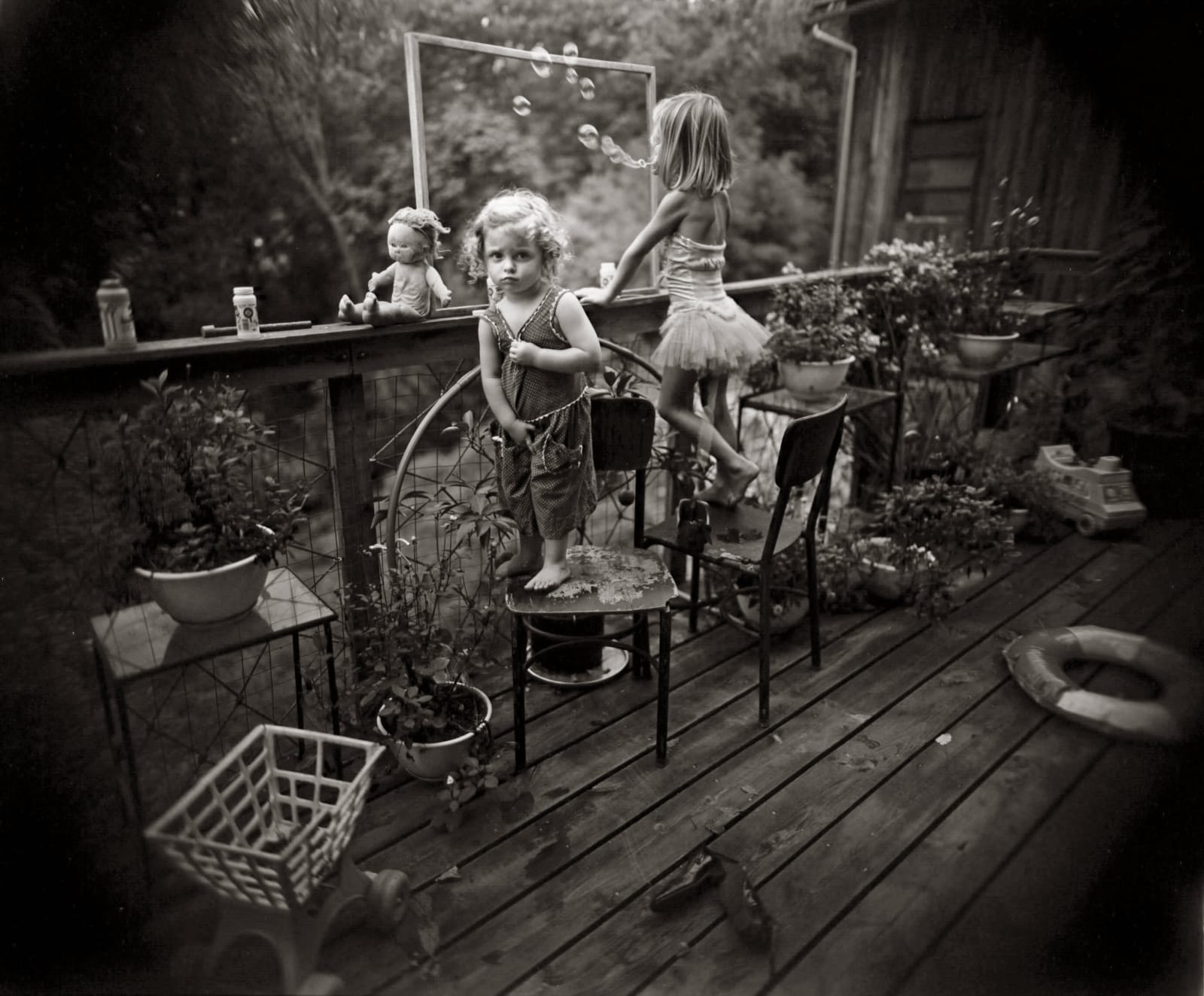 Virginia and Jessie blowing bubbles on outdoor porch, from the Immediate Family series, by Sally Mann