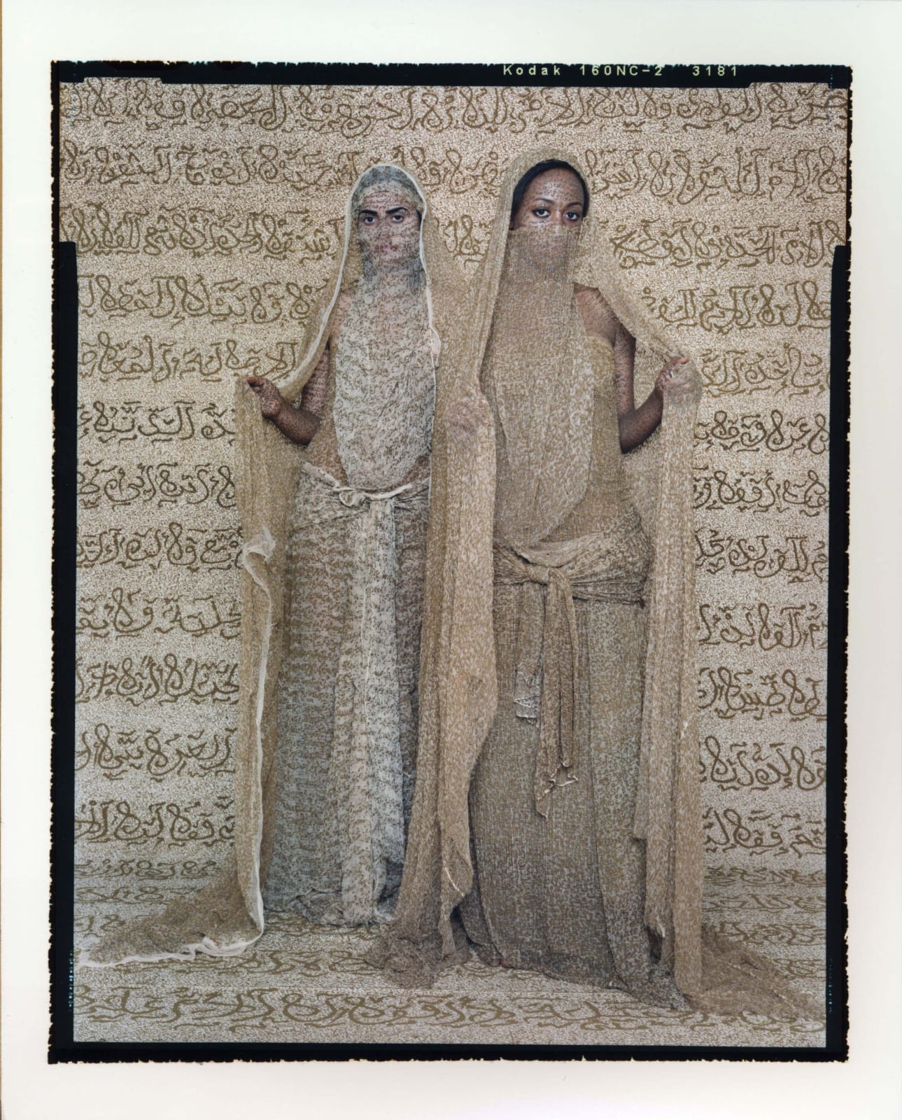 Two standing women wearing face veils with henna calligraphy inscribed on clothing fabric and skin, from the Les Femmes du Maroc series, by Lalla Essaydi