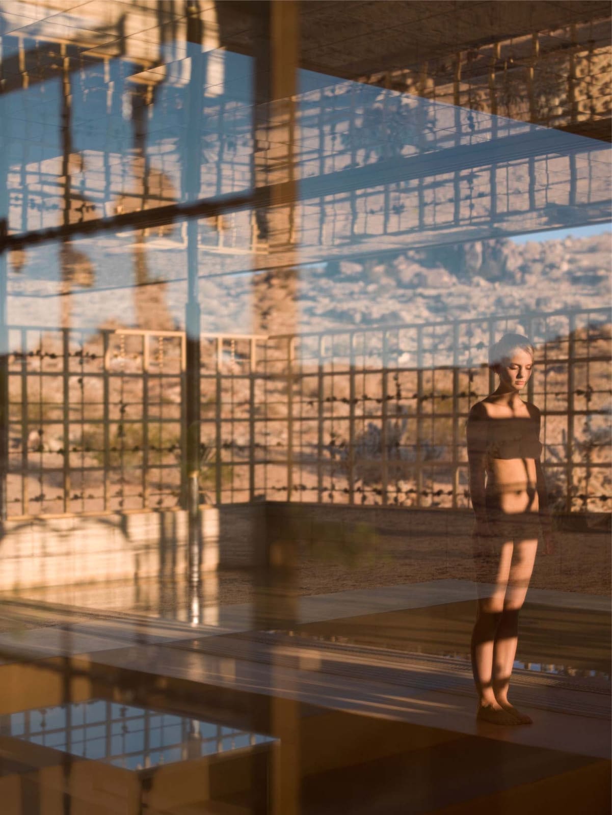 Woman standing nude in golden modernist structure in Joshua Tree California, by Mona Kuhn
