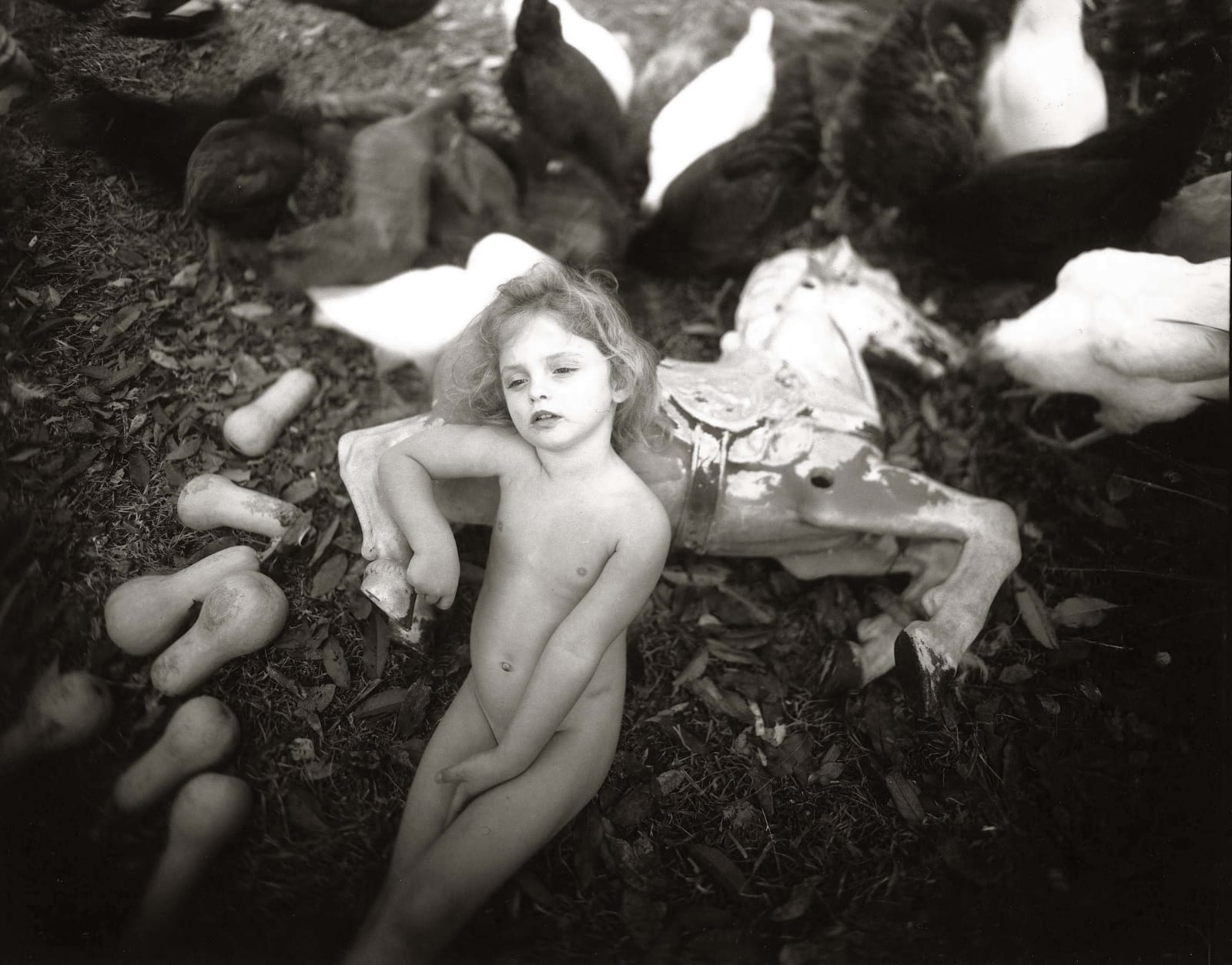 Virginia leaning against carousel pony with winter squash next to her, from the Immediate Family series by Sally Mann