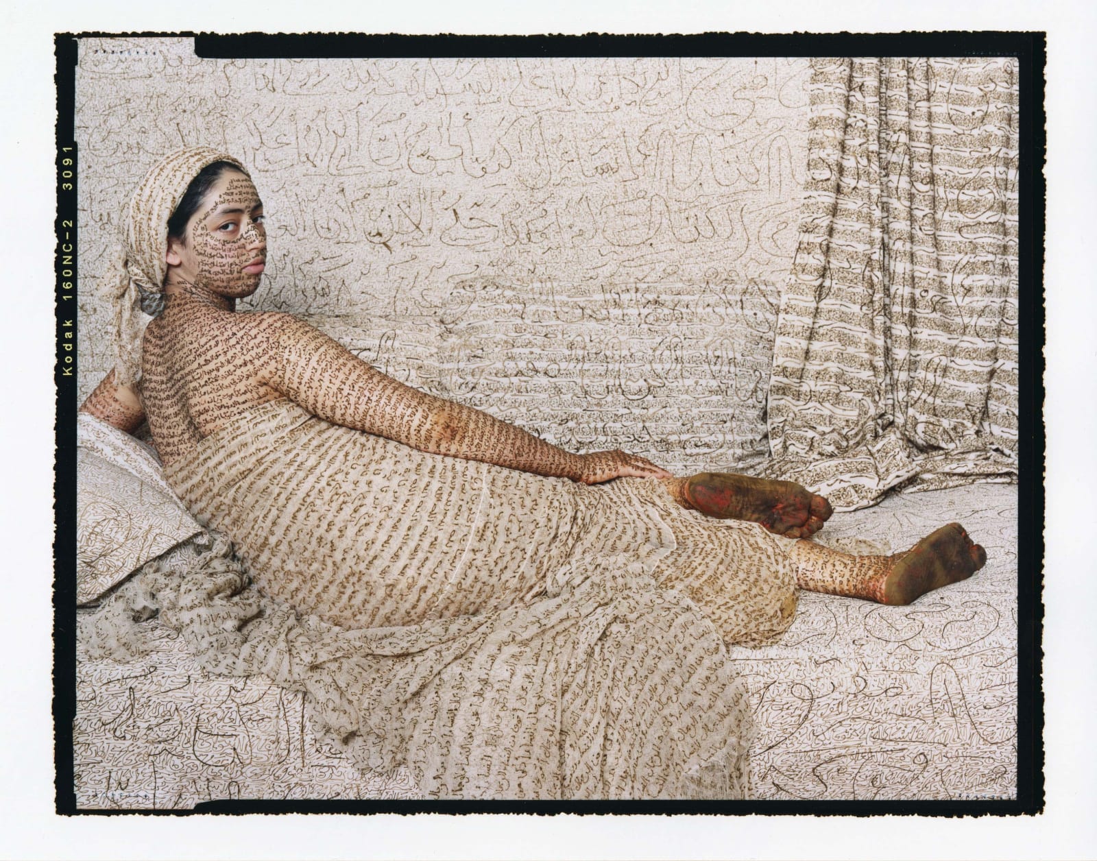 Lalla Essaydi Les Femmes du Maroc, woman posing to imitate subject in Jean Auguste Dominique Ingres' painting La Grande Odalisque, her skin and all fabric inscribed with Arabic calligraphy in henna