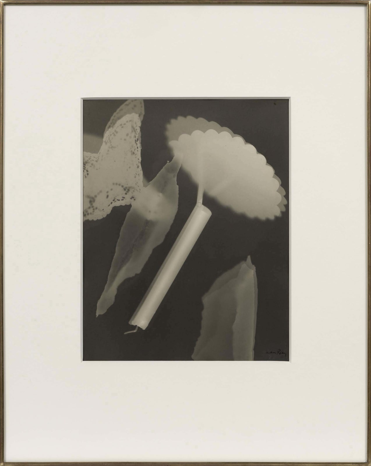 Man Ray Rayograph featuring abstract shapes, lace, and a scalloped object arranged in surreal composition on photographic paper without a camera.