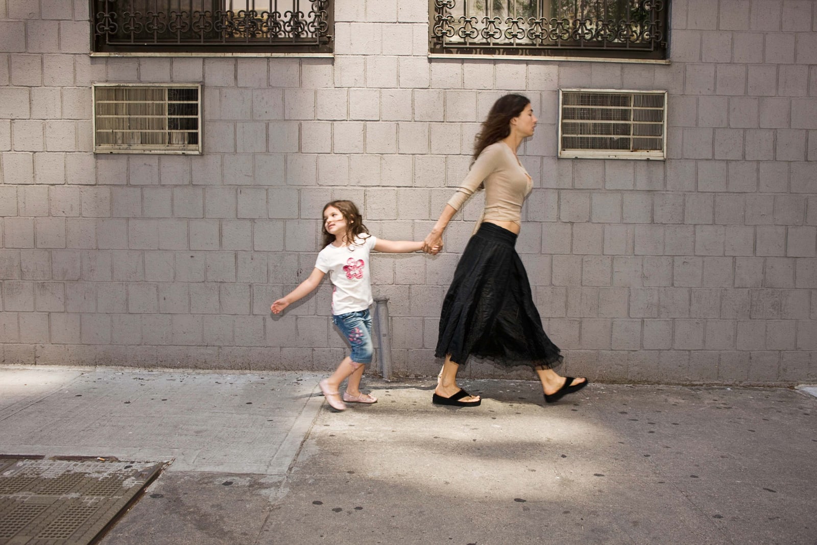Elinor Carucci photograph of the artist walking on the sidewalk holding her daughter's hand