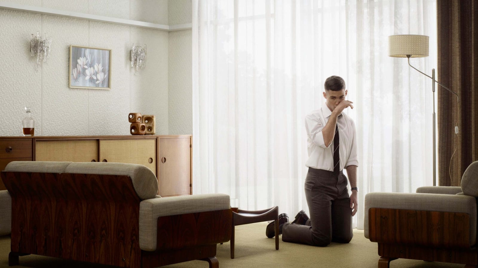Man crying on his knees in living room by Erwin Olaf
