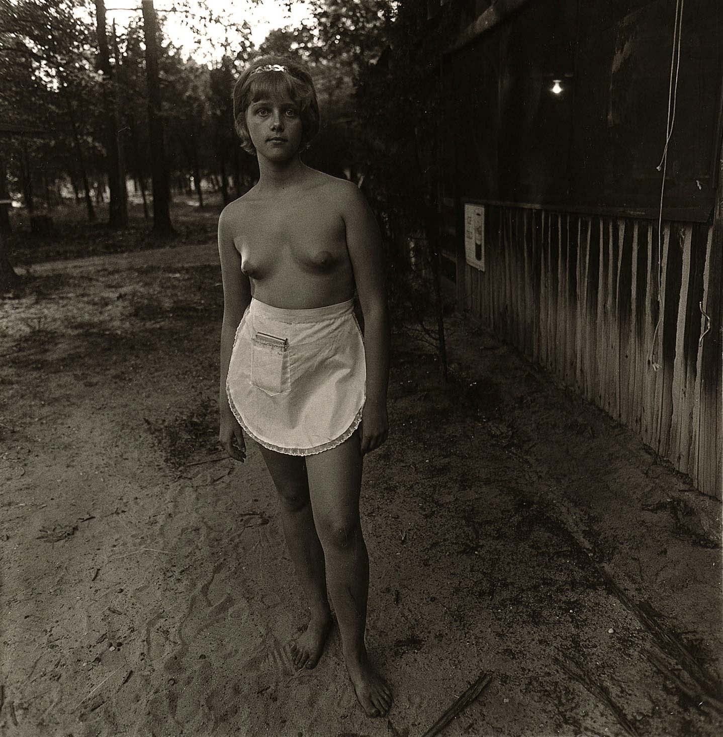 Diane Arbus photograph of nude waitress wearing only serving waist apron.