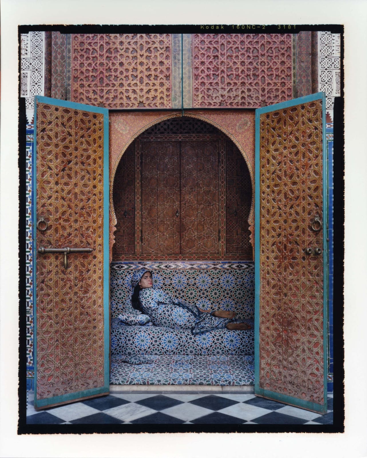 Woman reclining on divan in arched doorway, by Lalla Essaydi