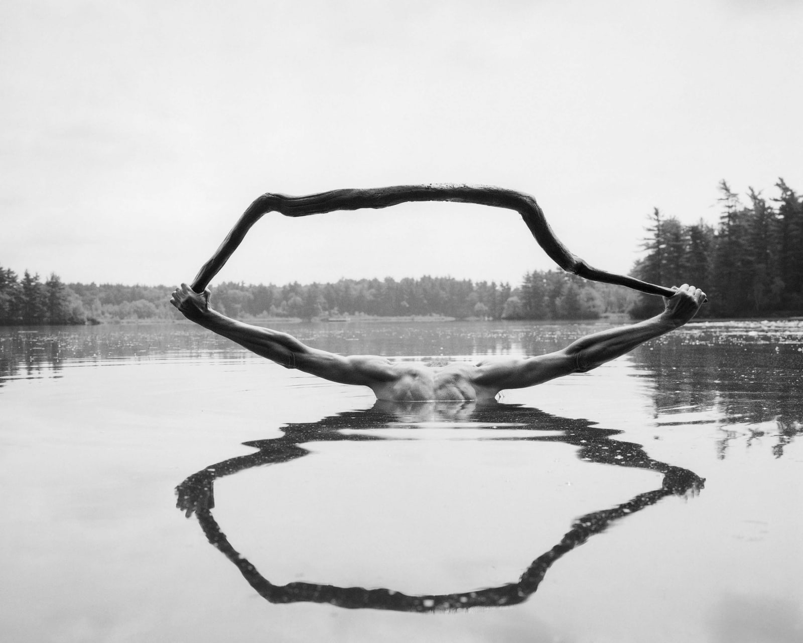 Arno Minkkinen Ismo's Stick, Fosters Pond straight photograph optical illusion of man's arms holding stick reflected in pond surface to make a figure eight