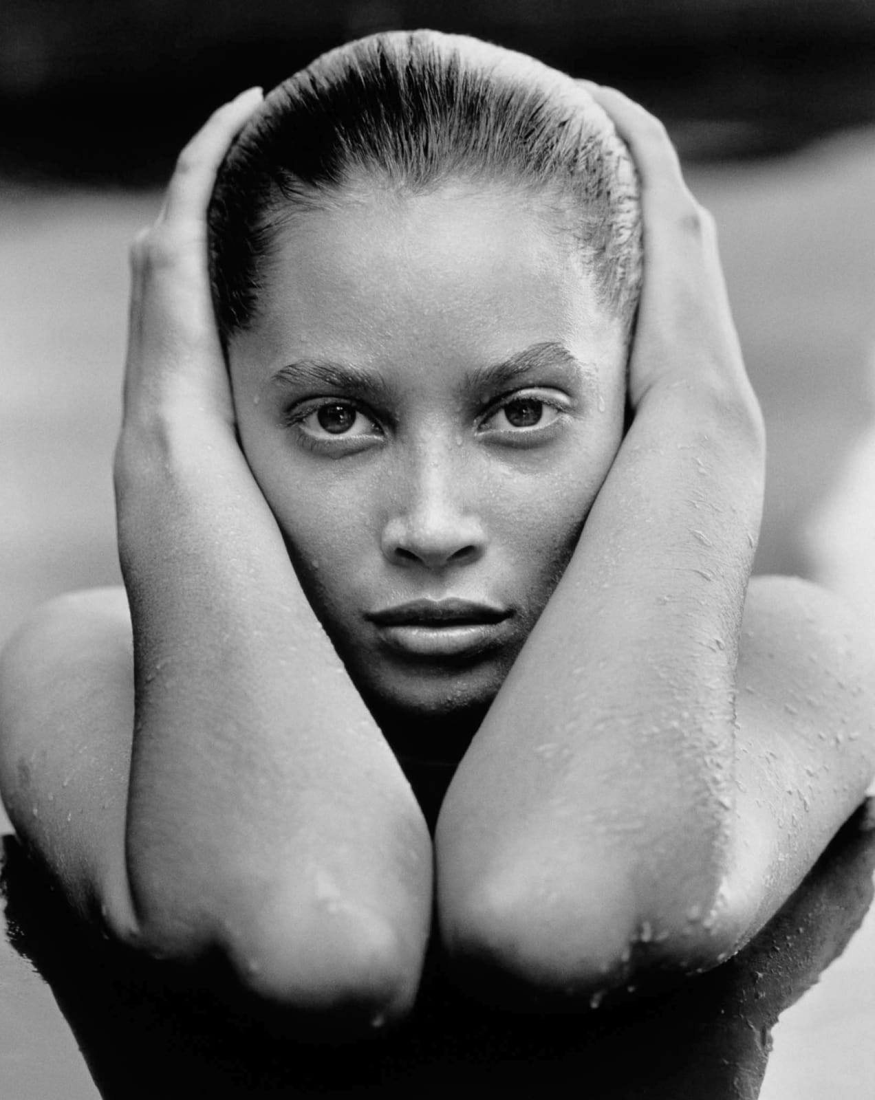Close-up portrait of Christy Turlington's face and arms in pool by Herb Ritts