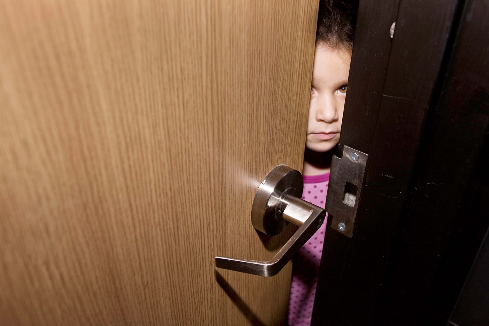 Elinor Carucci photograph of the artist's daughter looking at her from behind a door
