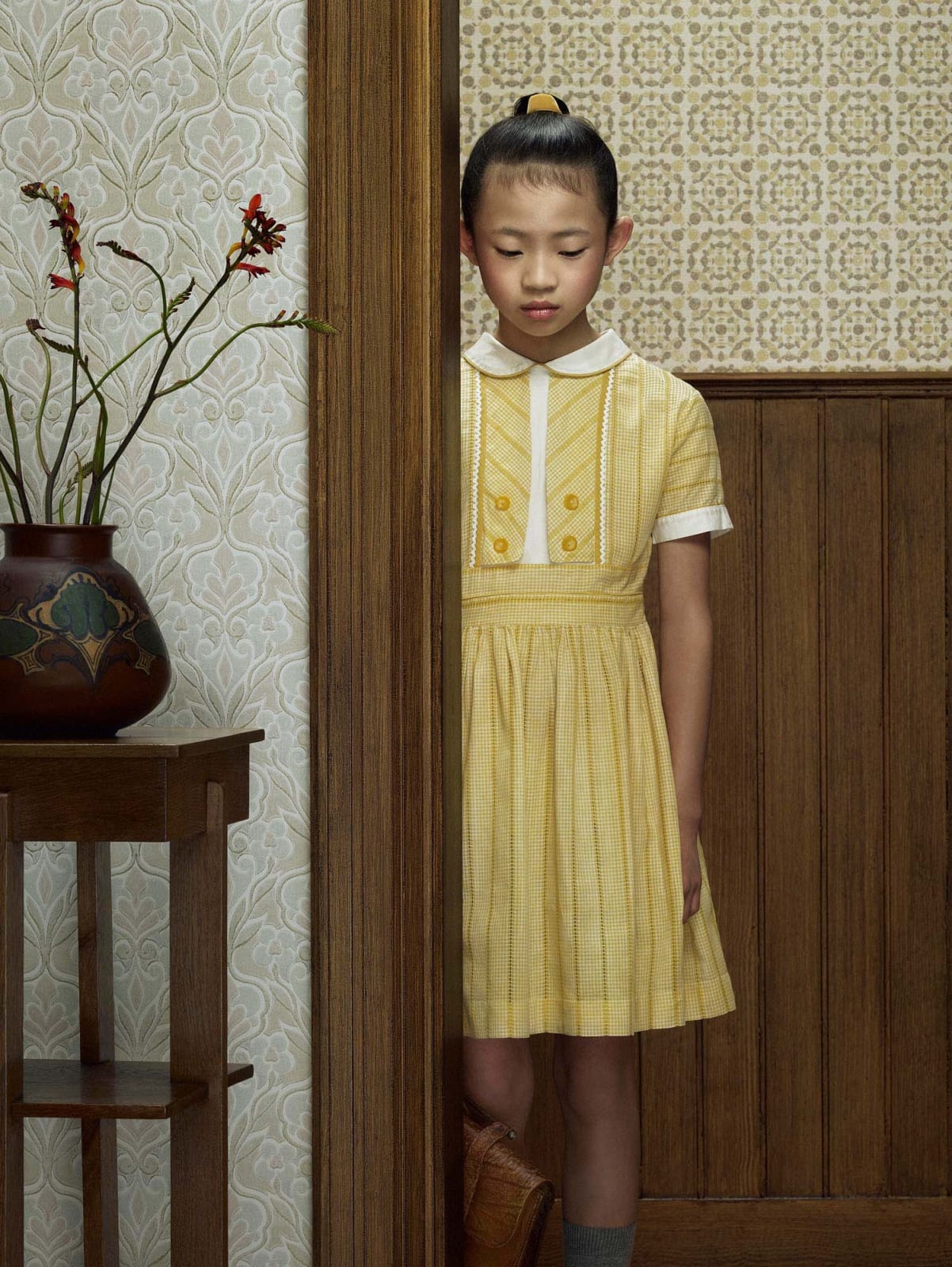 Girl in yellow dress standing in doorway by Erwin Olaf