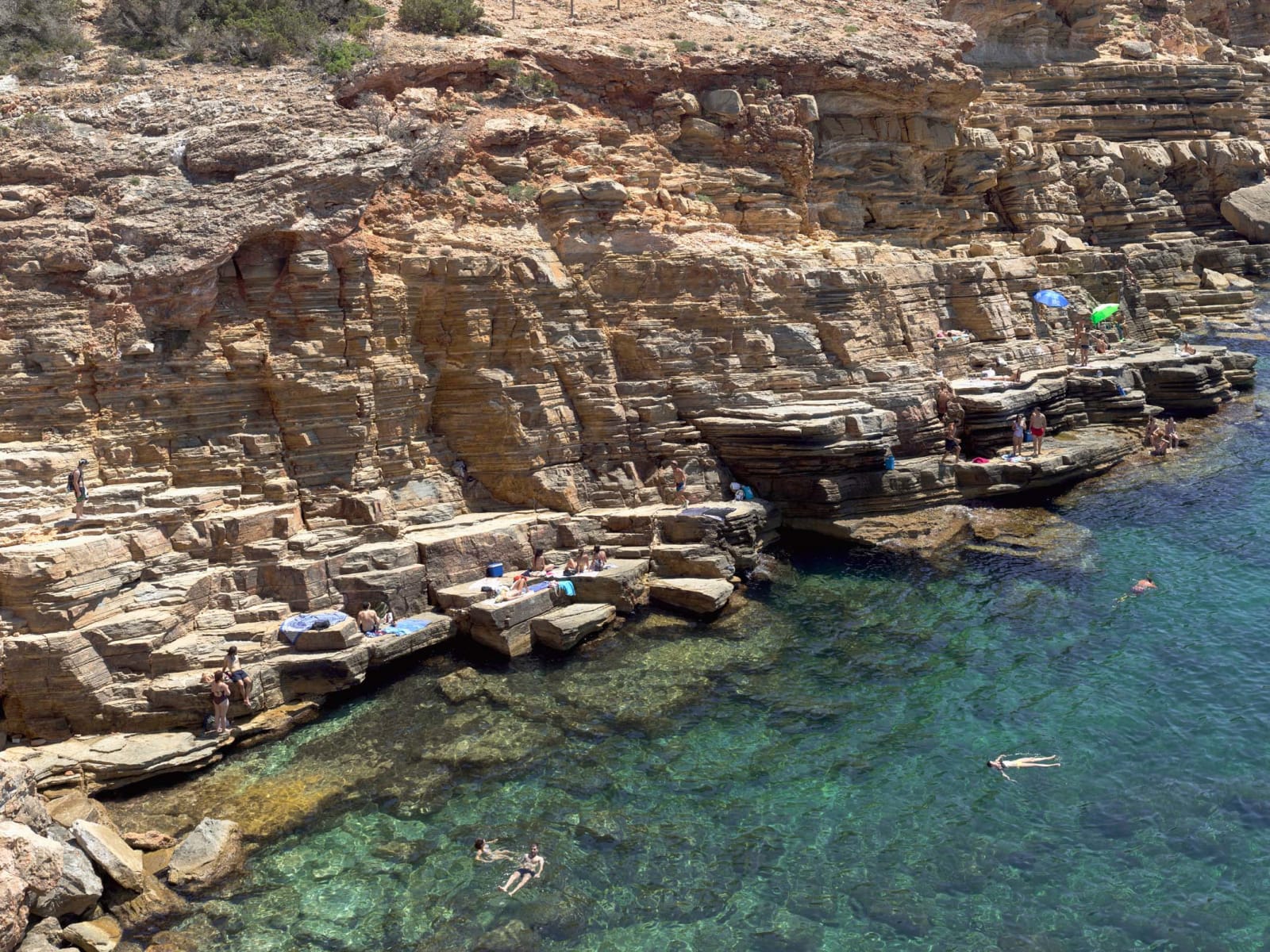 Beachgoers floating in blue water at Cala Llosa South, Ibiza, by Massimo Vitali